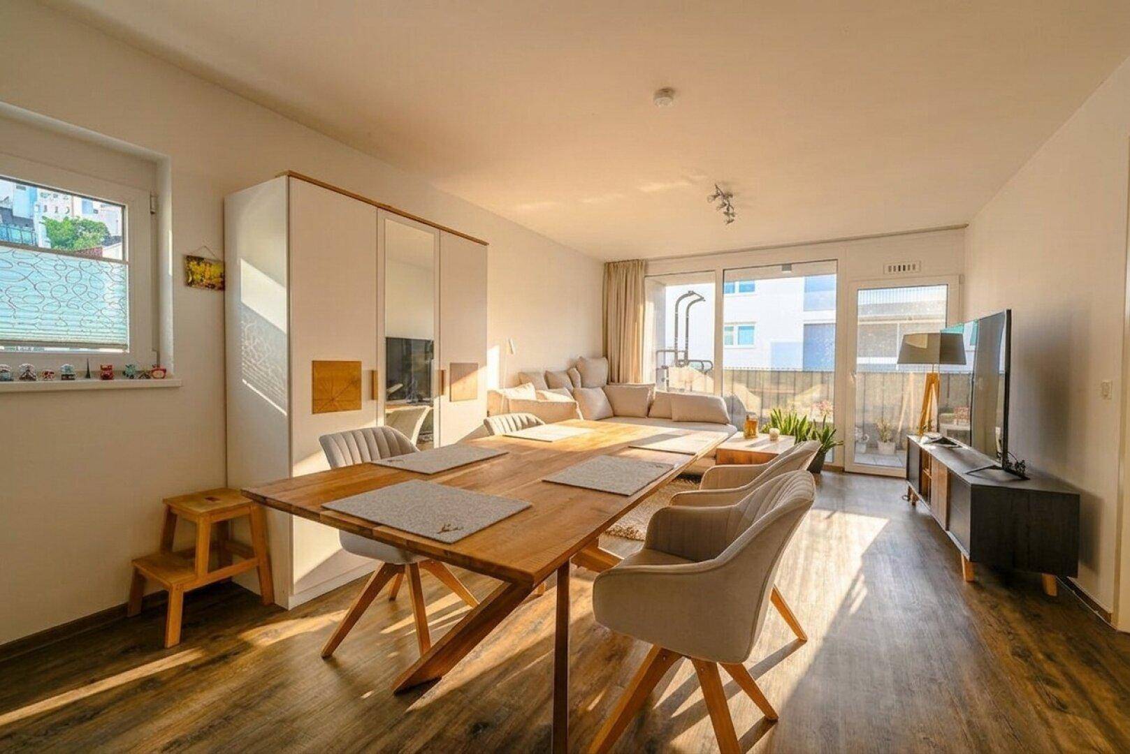 Lichtdurchfluteter Wohn-Essbereich mit Zugang zum Balkon und Blick nach draußen.