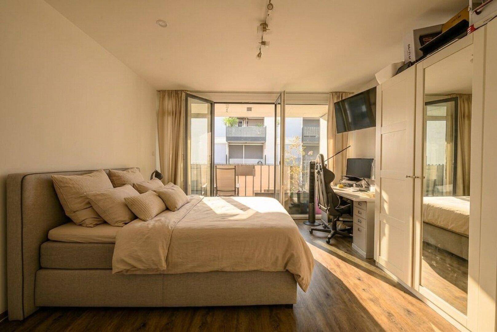 Helles Schlafzimmer mit Doppelbett, Schreibtisch und direktem Zugang zum Balkon.