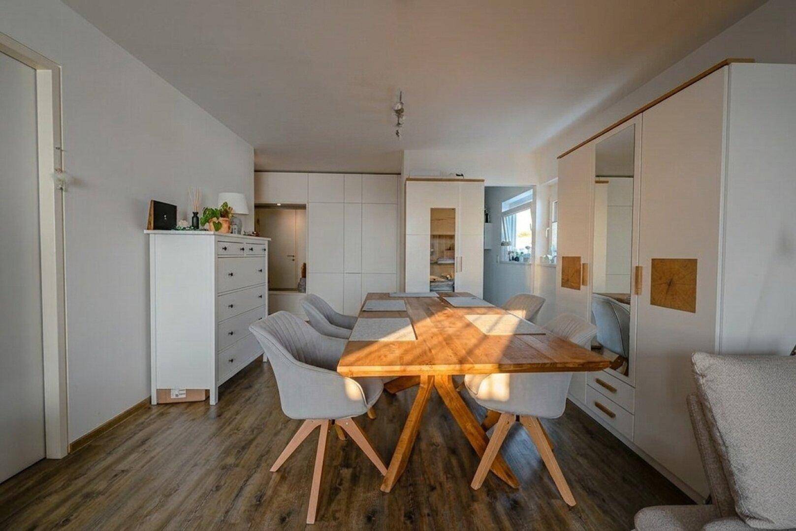 Geräumiger Wohn-Essbereich mit Holzboden und integrierten Schränken für Stauraum.