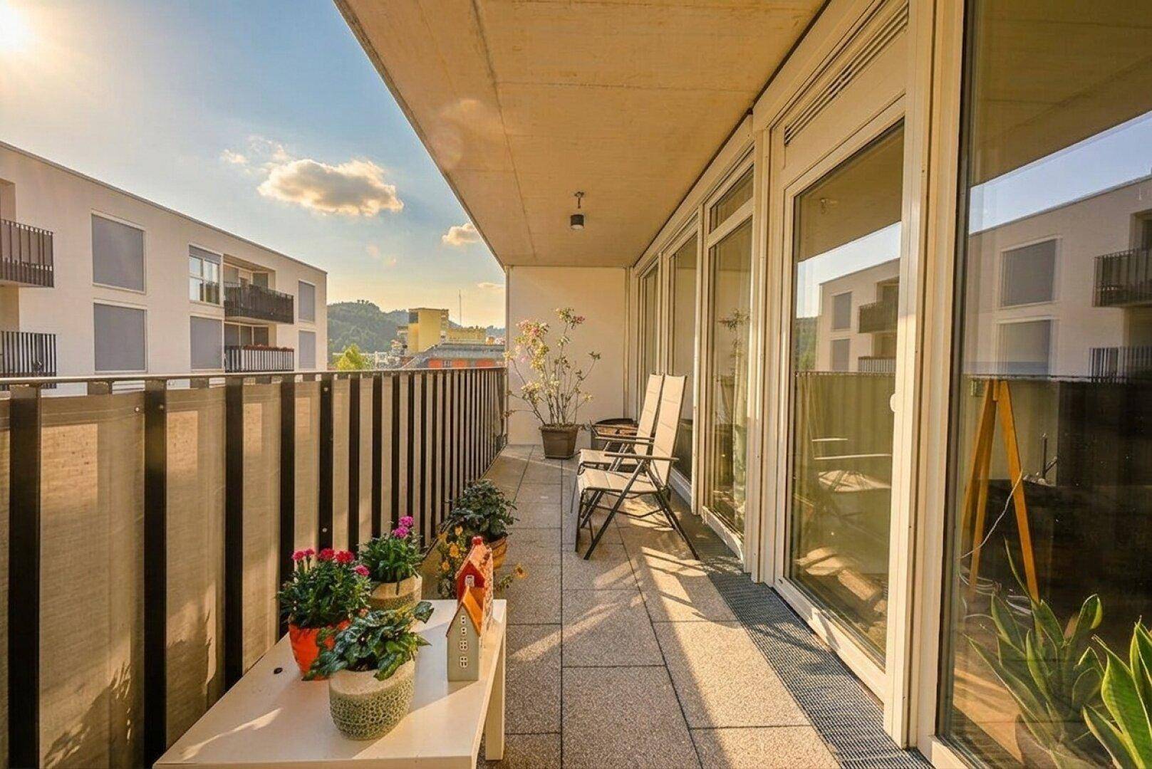 Sonniger Balkon mit Sitzgelegenheiten und Blick auf die umliegenden Gebäude.