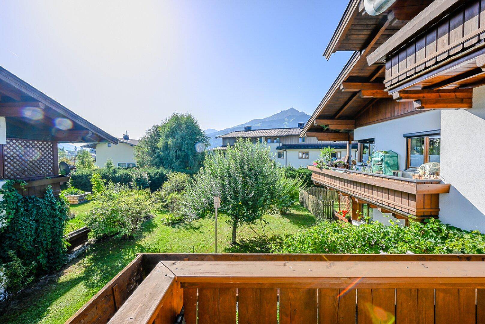 Weitläufiger Gartenbereich mit Rasen, Bäumen und Blick auf die Berge.