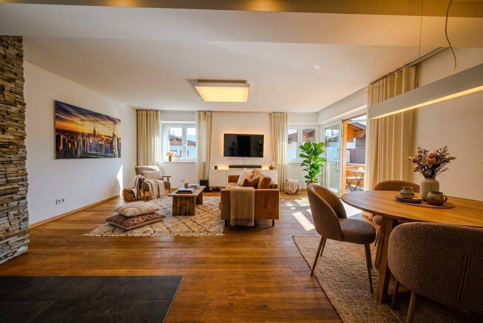 Gemütlicher Wohnbereich mit Holzboden, Teppichen und Zugang zu einem Außenbereich.