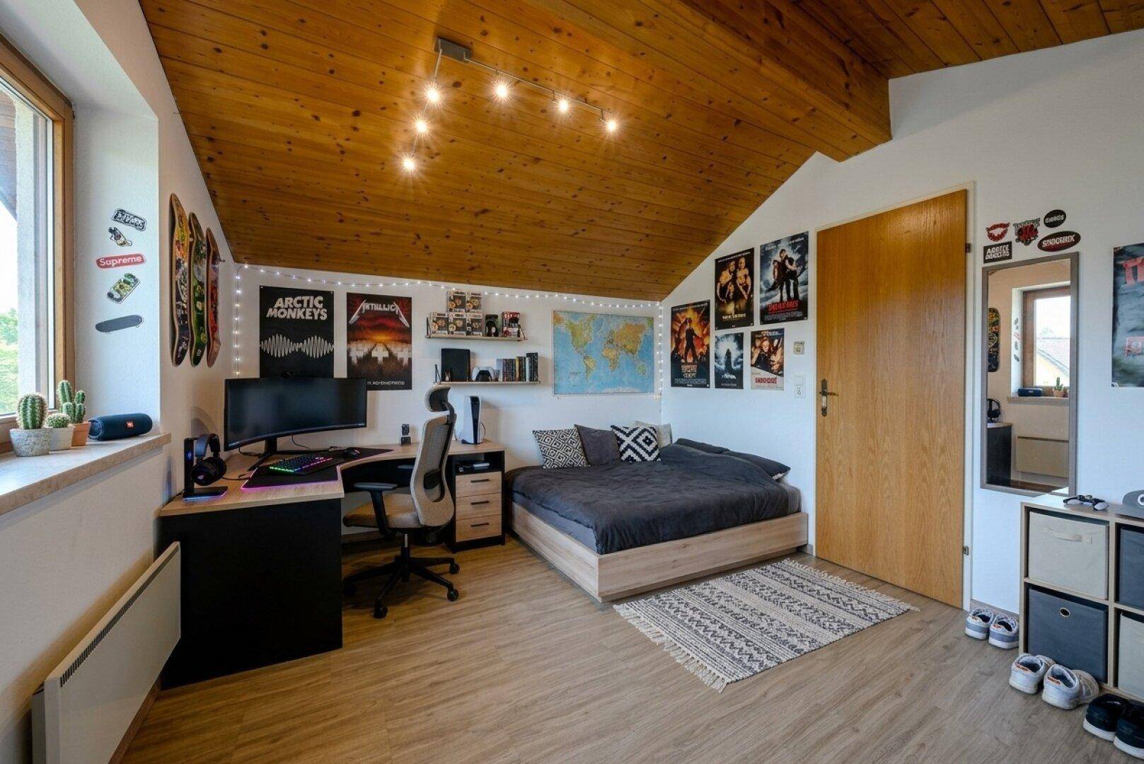 Jugendzimmer mit Holzdecke, Schreibtisch, Bett und kreativer Wandgestaltung.