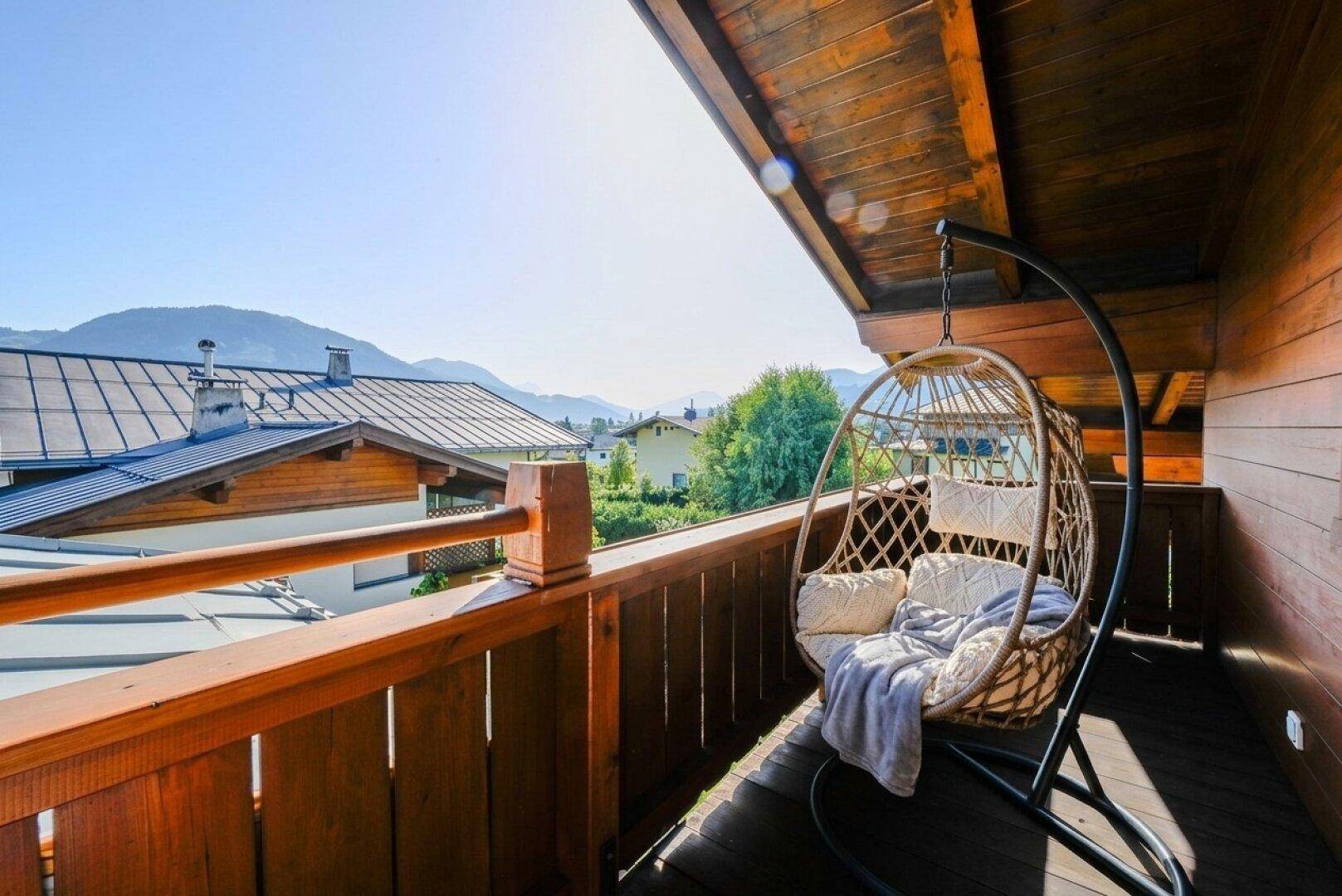 Gemütlicher Balkon mit Hängesessel, Holzverkleidung und weitem Bergblick.