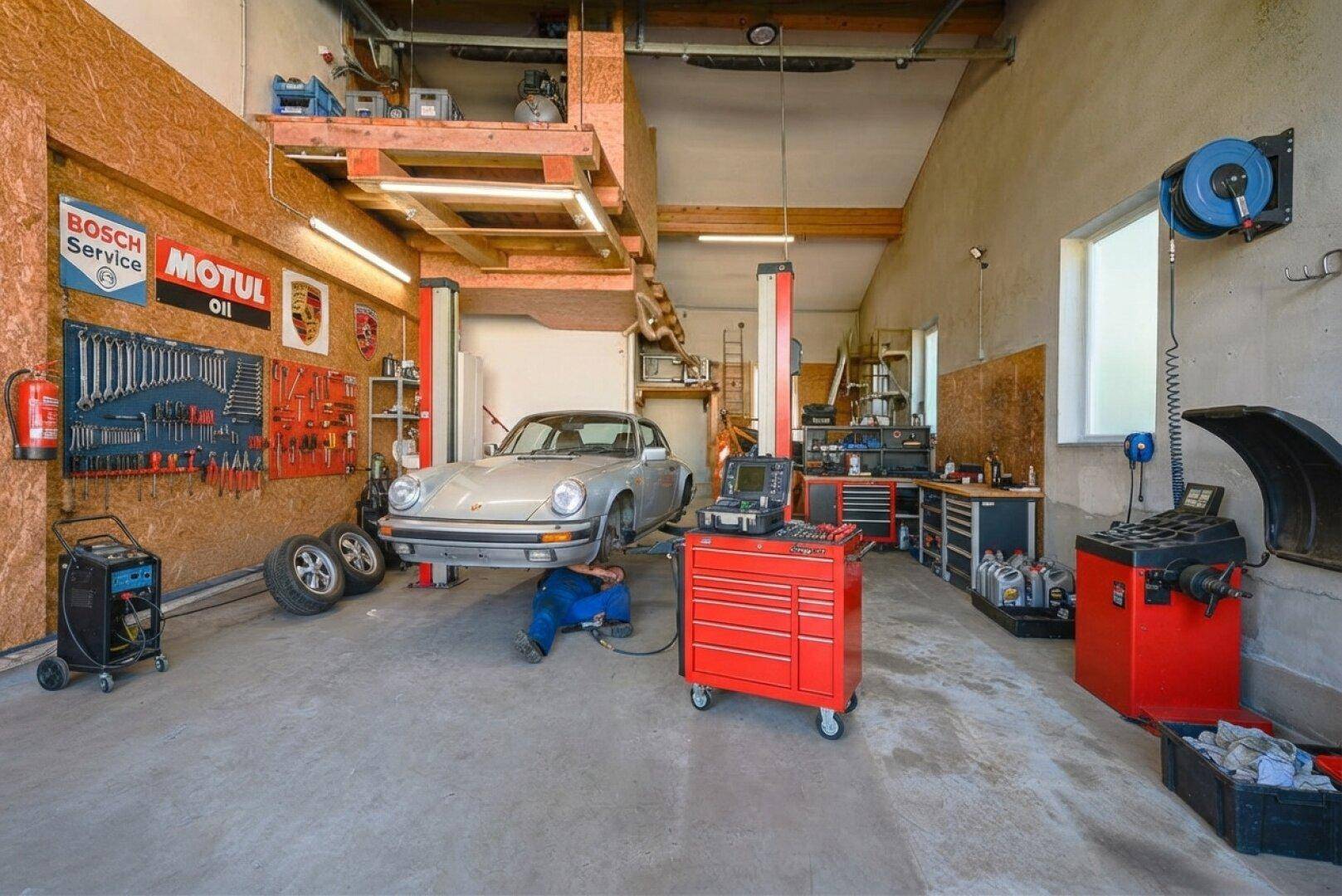 Professionelle Werkstatt in der Garage mit Hebebühne, Werkzeugen und Diagnosegeräten.