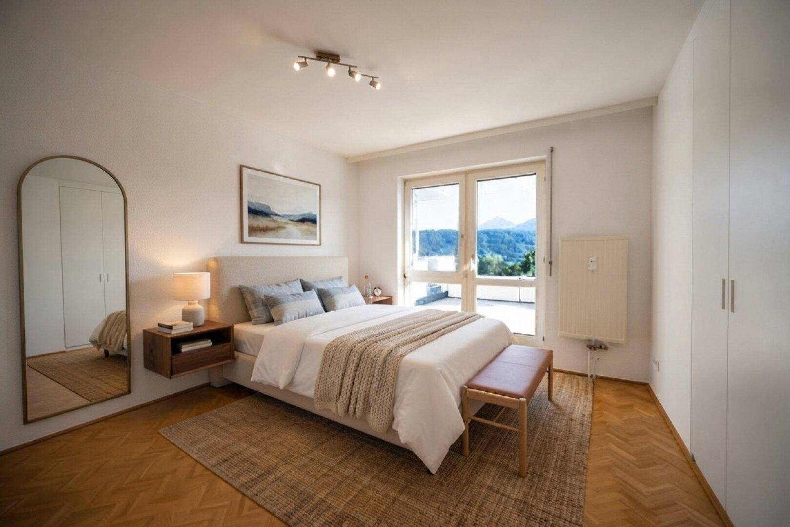 Helles Schlafzimmer mit Holzboden, großem Bett und Zugang zum Balkon mit Bergblick.