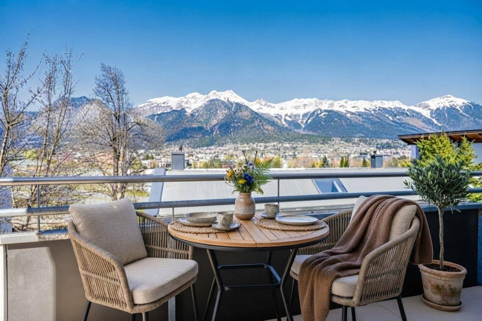Kleiner Balkon mit Bistrotisch und Stühlen, ideal für Frühstück mit Bergblick.