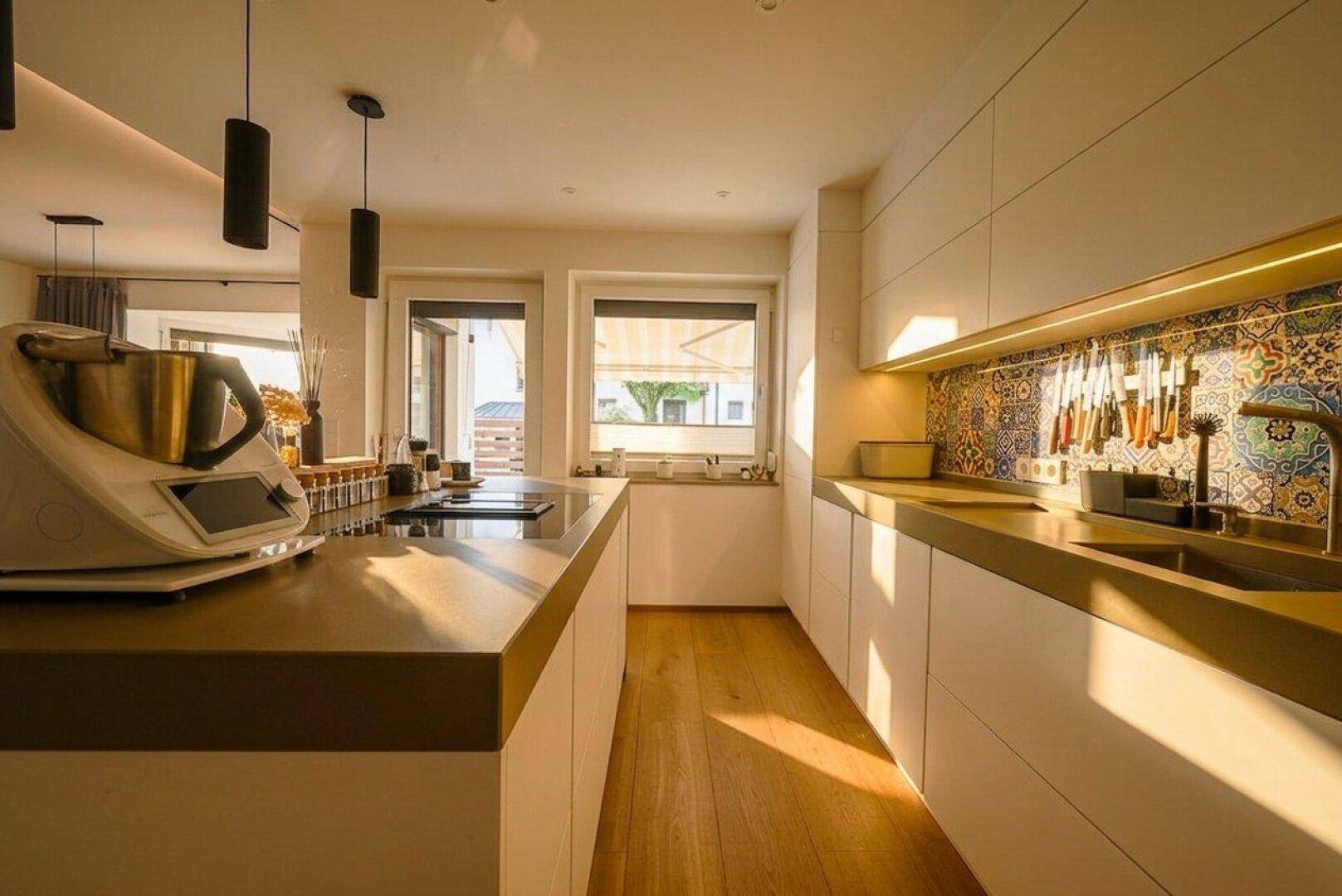 Moderne Küche mit weißen Schränken, Holztheken und farbenfrohem Fliesenspiegel.