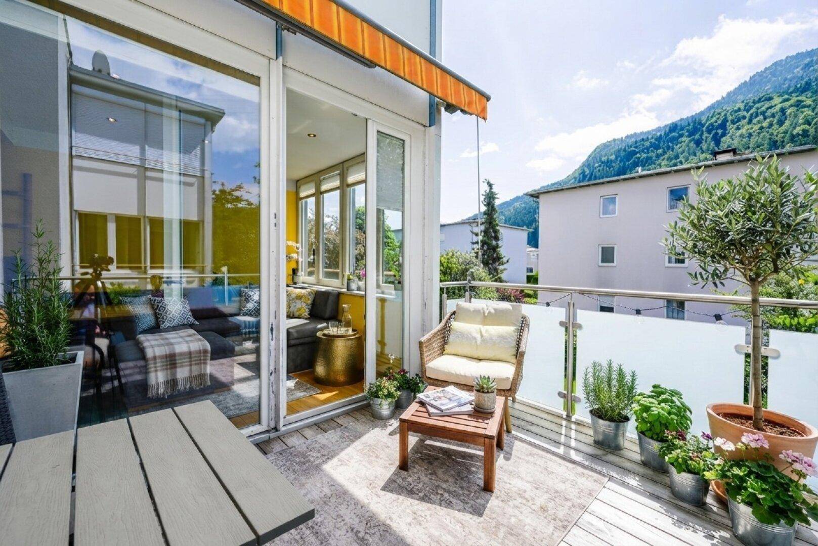 Heller Balkon mit Bergblick und Zugang zu einem verglasten Wintergarten, ideal zum Entspannen.
