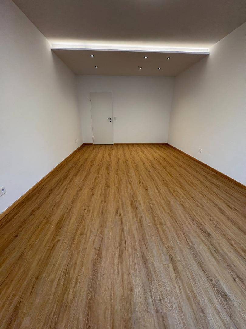 Geräumiger, heller Raum mit Laminatboden und moderner Deckenbeleuchtung, ideal für Büro oder Wohnen.