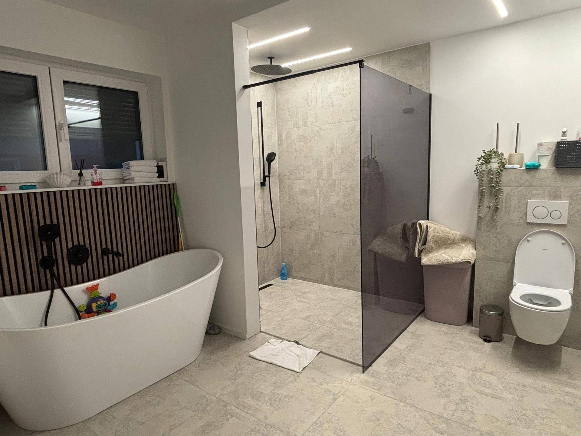 Modernes Badezimmer mit freistehender Badewanne, begehbarer Dusche und Wand-WC.