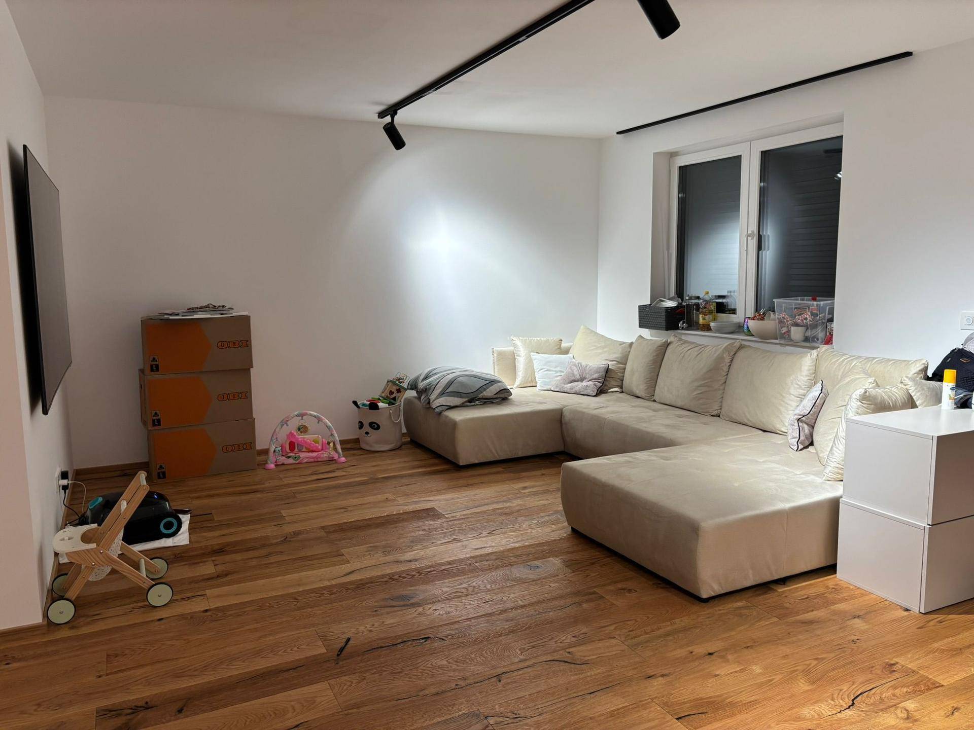 Gemütliches Wohnzimmer mit großem Ecksofa, Holzboden und natürlichem Lichteinfall.