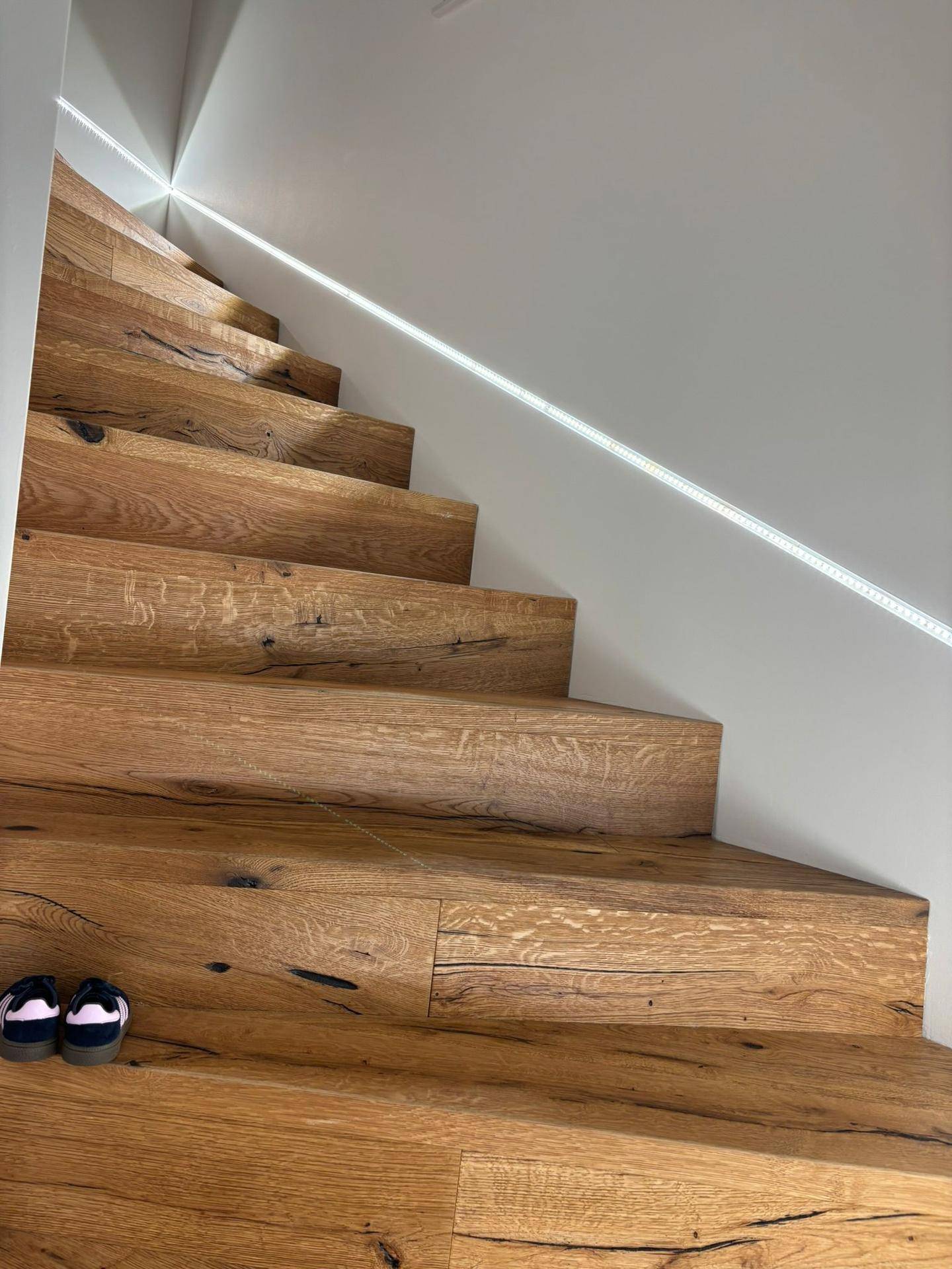 Moderne Holztreppe mit integrierter LED-Beleuchtung und klaren Linien.
