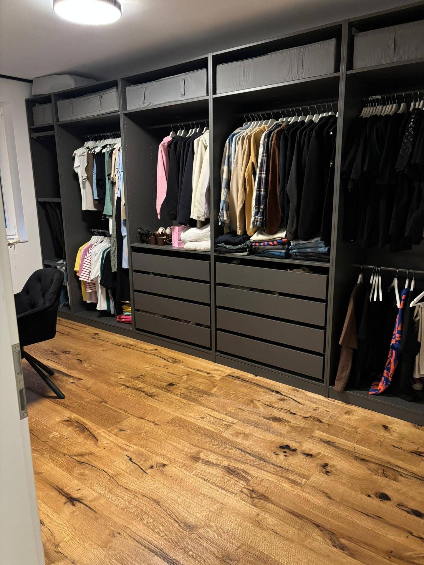 Geräumiger begehbarer Kleiderschrank mit viel Stauraum und Holzboden.