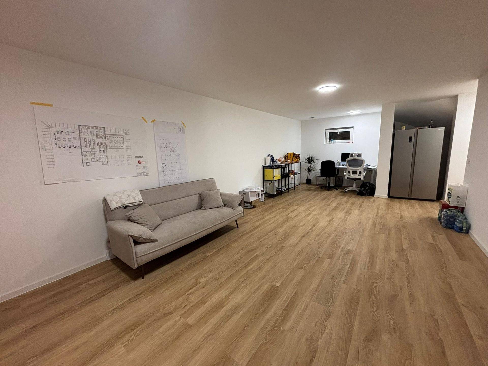 Ausgebauter Kellerraum mit Vinylboden, genutzt als Büro und Wohnbereich.