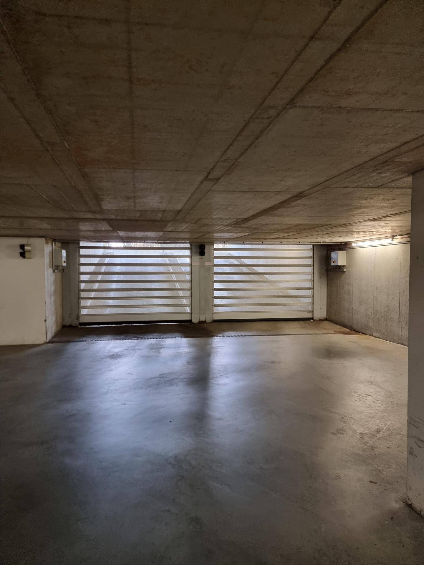 Geräumige Tiefgarage mit Betonstruktur und einem modernen automatischen Garagentor.