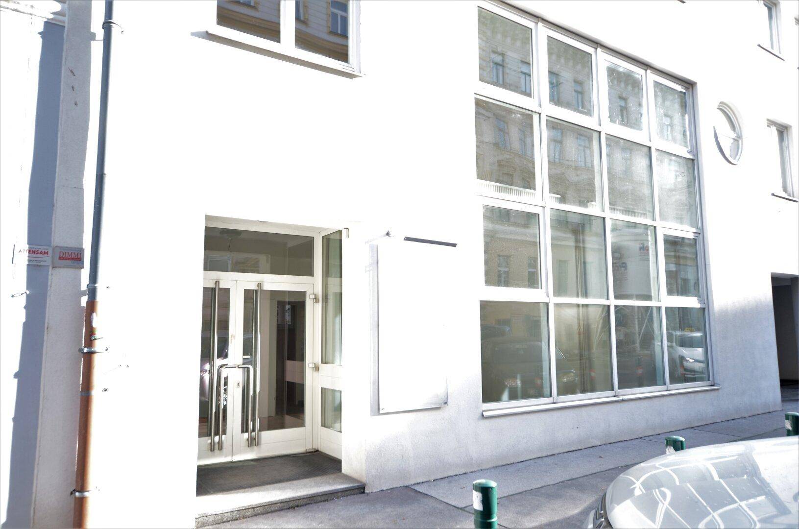 Moderne Gebäudefassade mit großen Glasfenstern und einem einladenden Eingangsbereich.