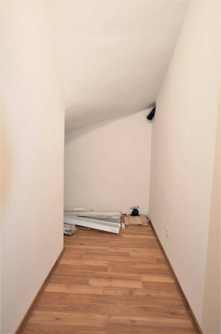 Schmaler Abstellraum mit Dachschräge und Laminatboden, ideal für Lagerzwecke.