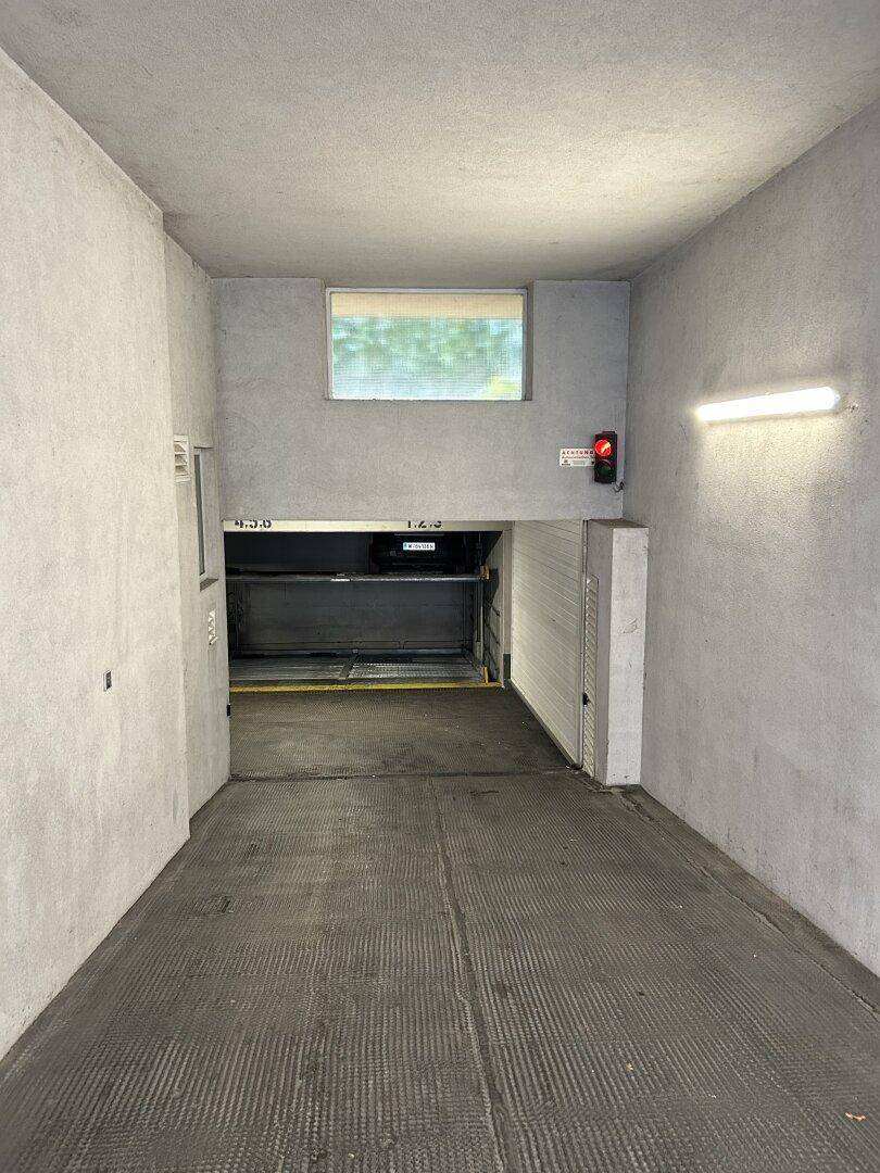 Innenansicht einer Tiefgarage mit automatischem Parksystem und einem kleinen Fenster für Tageslicht.