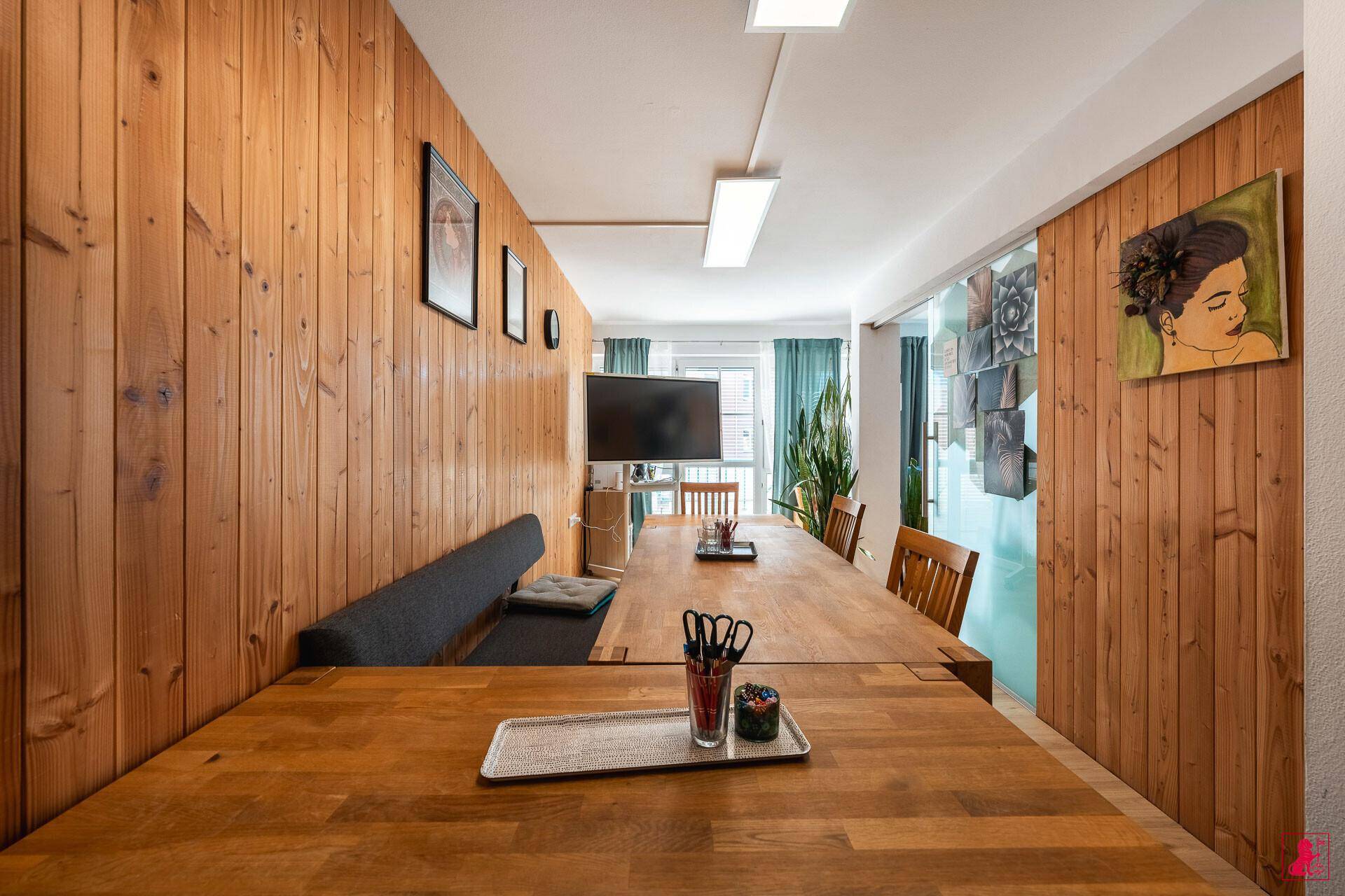 Langer Besprechungstisch mit Holzvertäfelung an der Wand und einem Flachbildfernseher für Präsentationen.