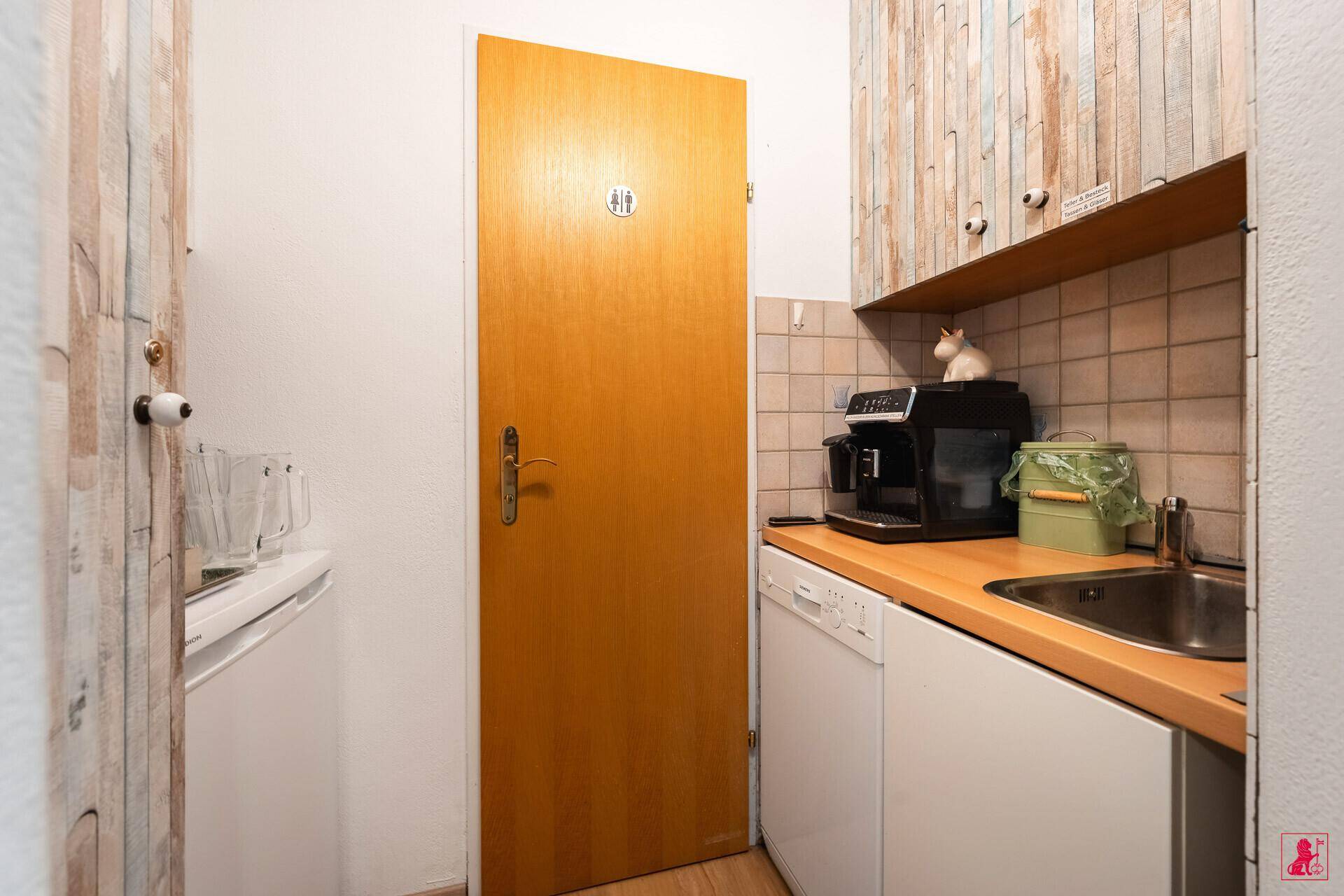 Kleine Küchenzeile mit Spüle, Kaffeemaschine und Geschirrspüler, ideal für eine schnelle Pause.