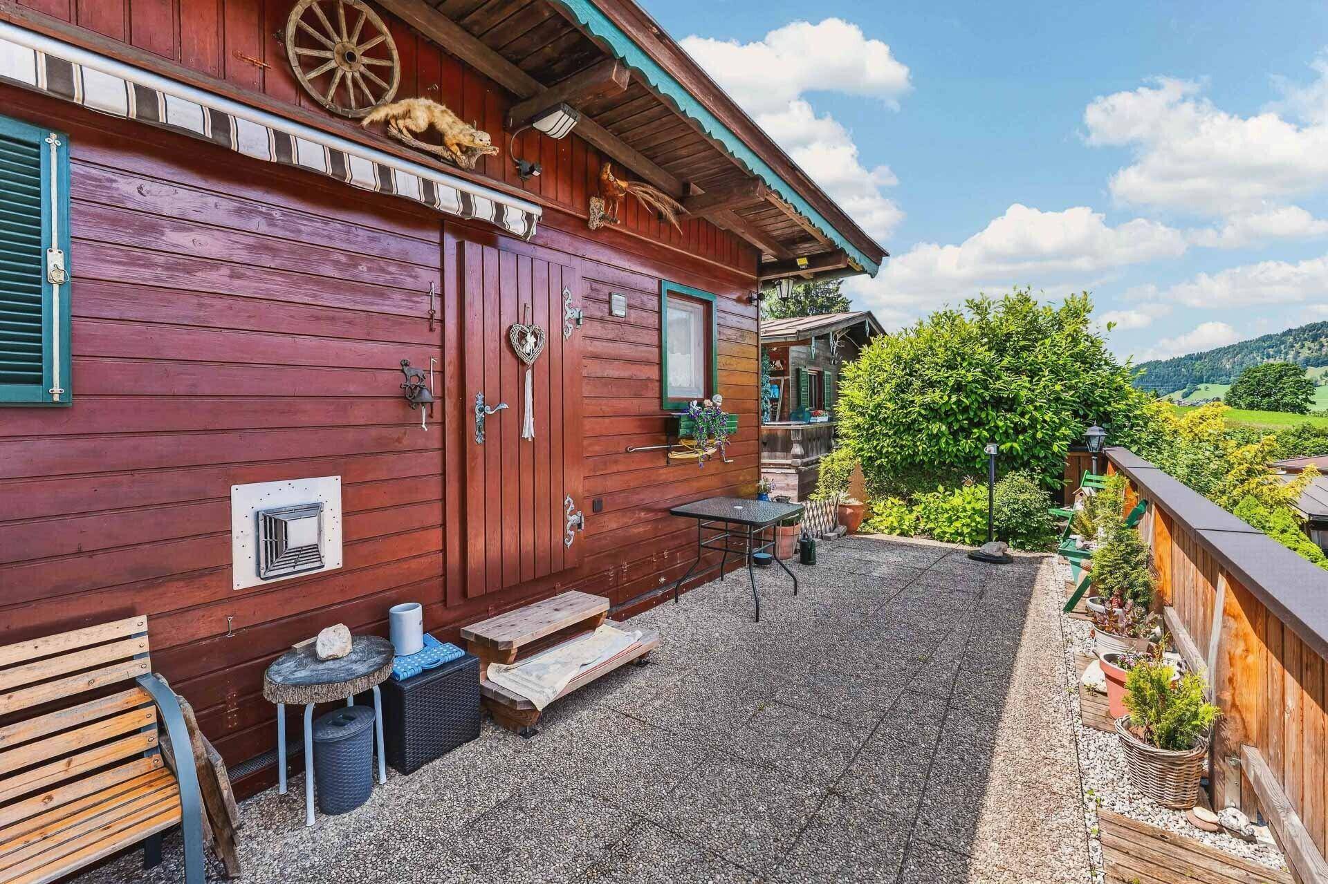 Seitlicher Terrassenbereich am Holzhaus mit rustikalen Dekorationen und Sitzgelegenheiten.