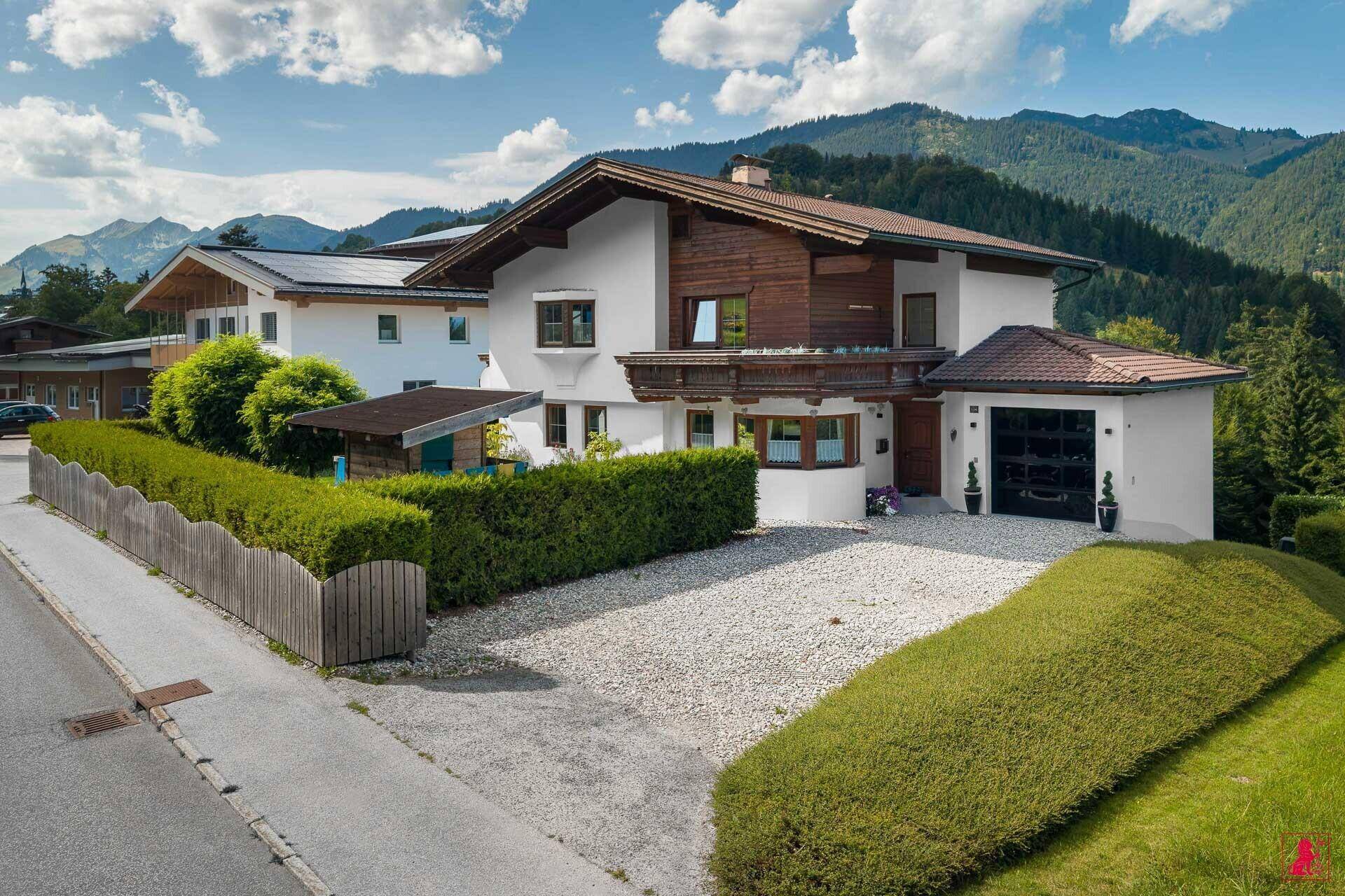 Vorderansicht des Hauses mit Kiesauffahrt, Garage und umgebender Hecke.