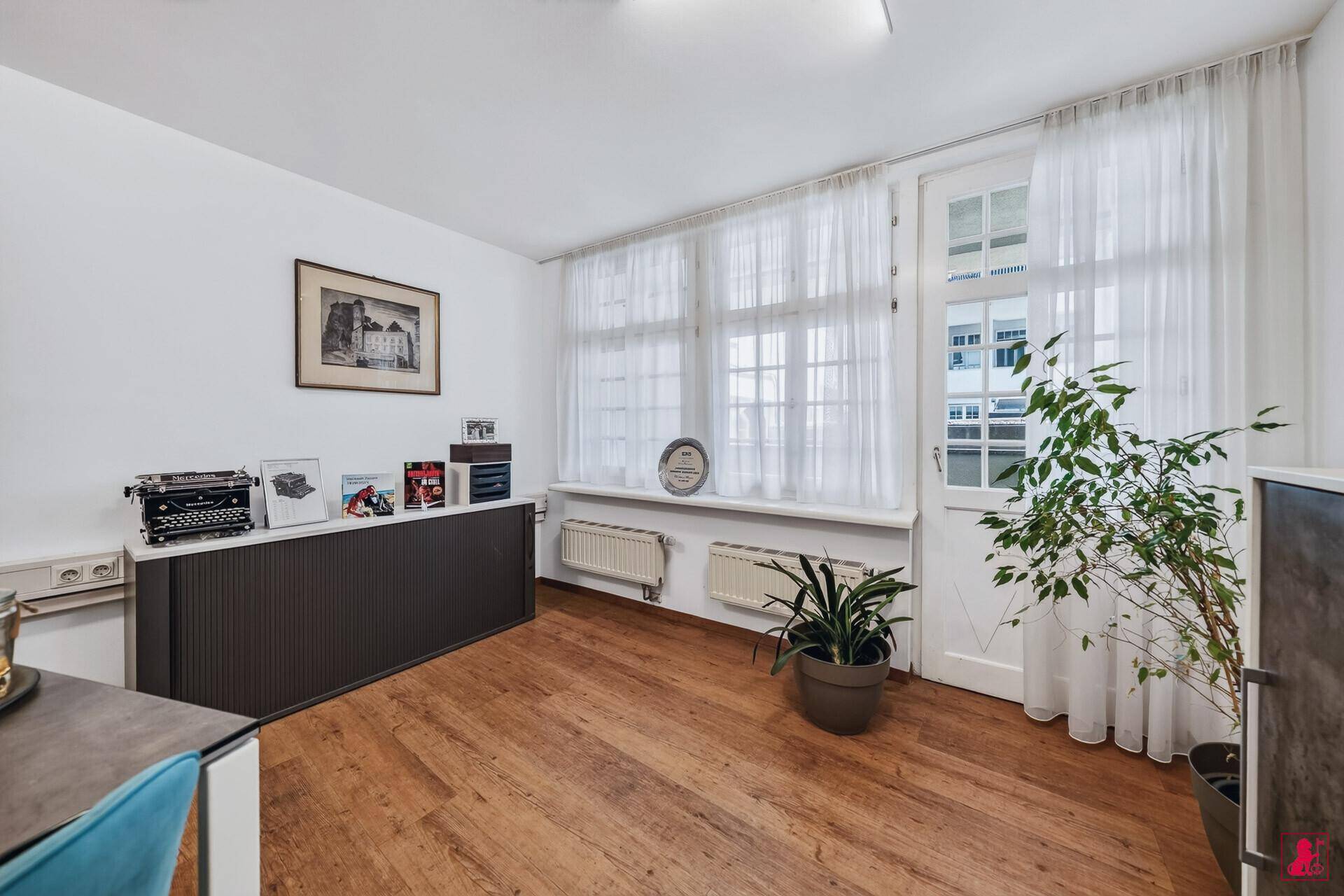 Heller Büroraum mit großen Fenstern, die viel Tageslicht spenden, und einem modernen Sideboard.