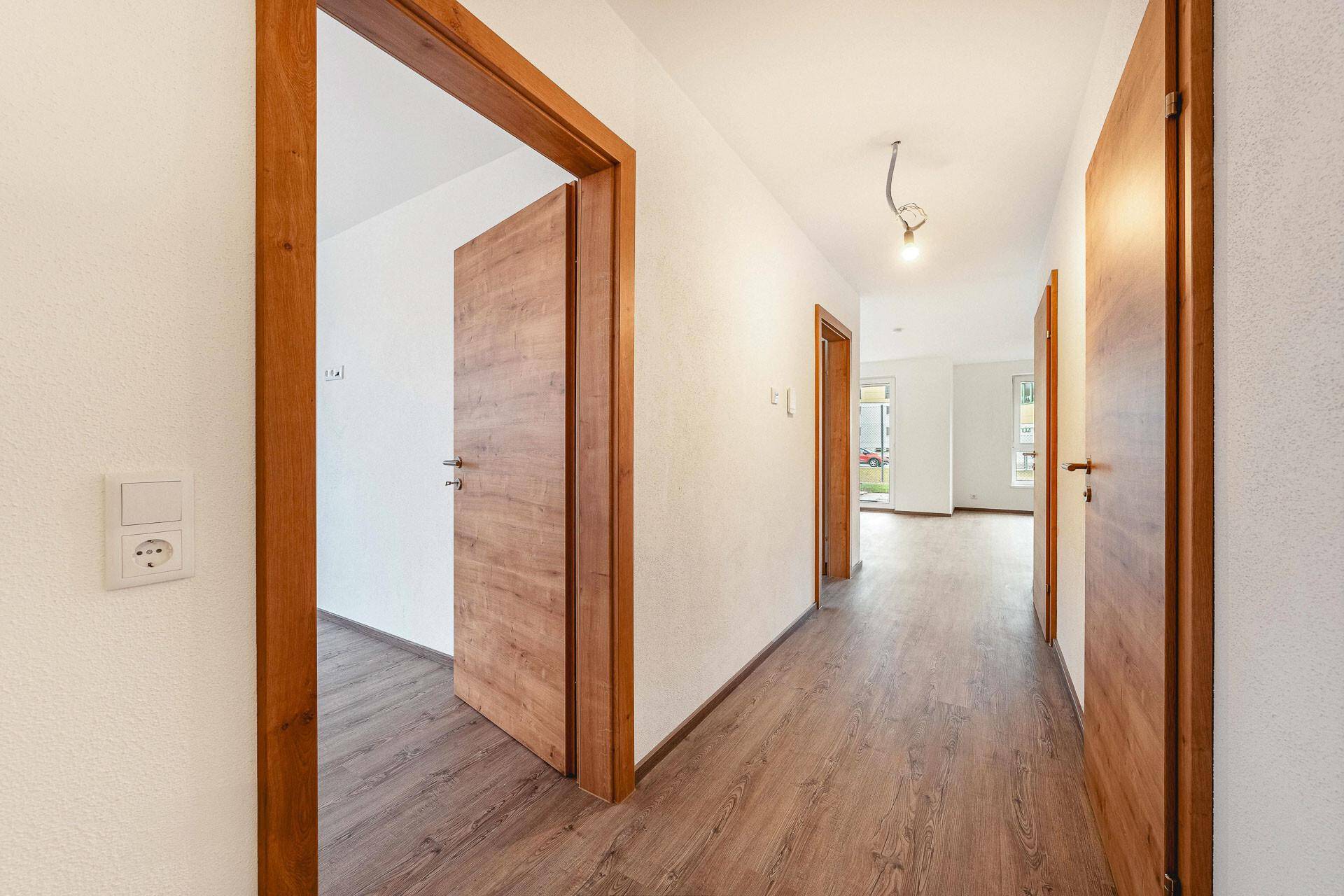 Geräumiger Flur mit Holztüren und Laminatboden, der die verschiedenen Wohnbereiche verbindet.