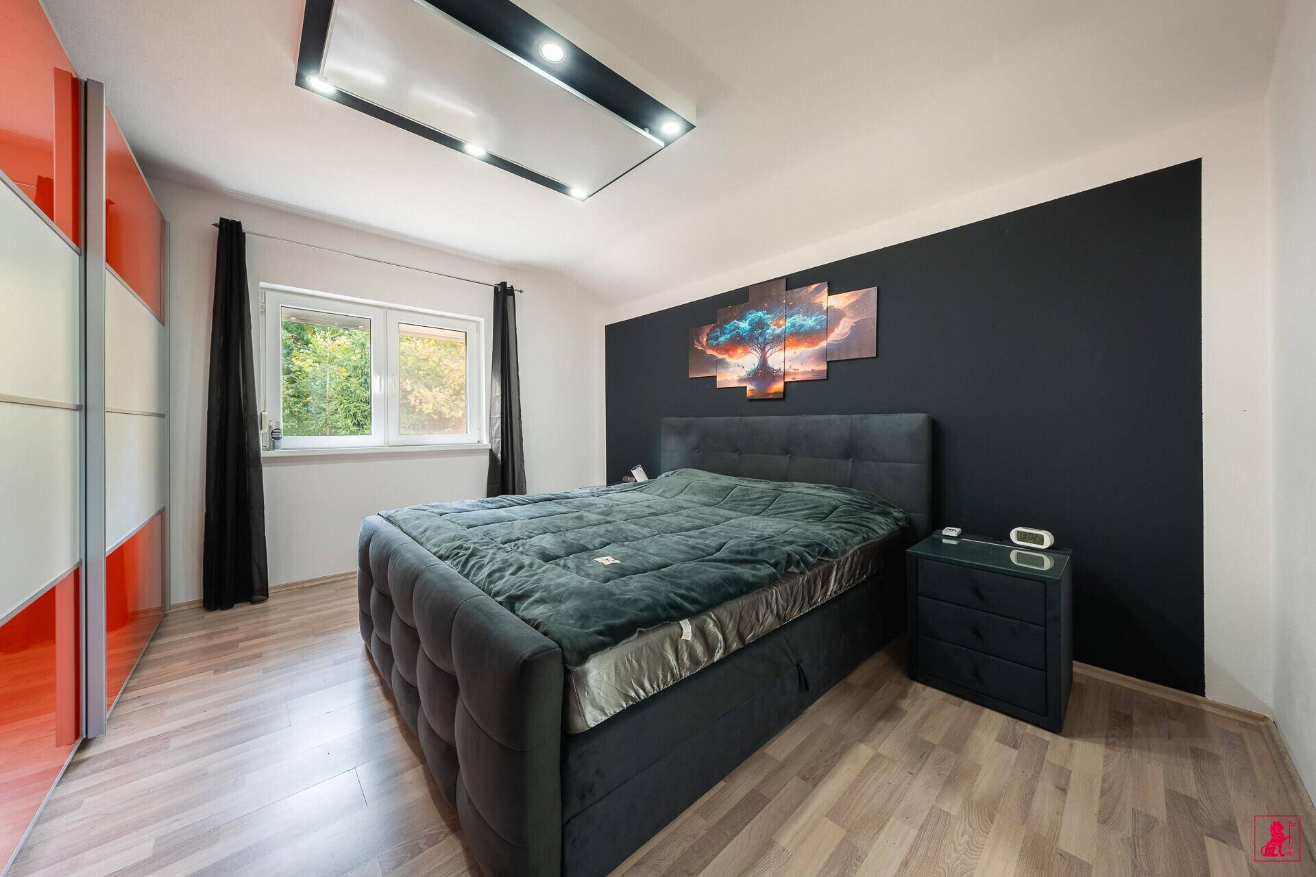 Modernes Schlafzimmer mit dunkler Akzentwand, Doppelbett und Holzboden.