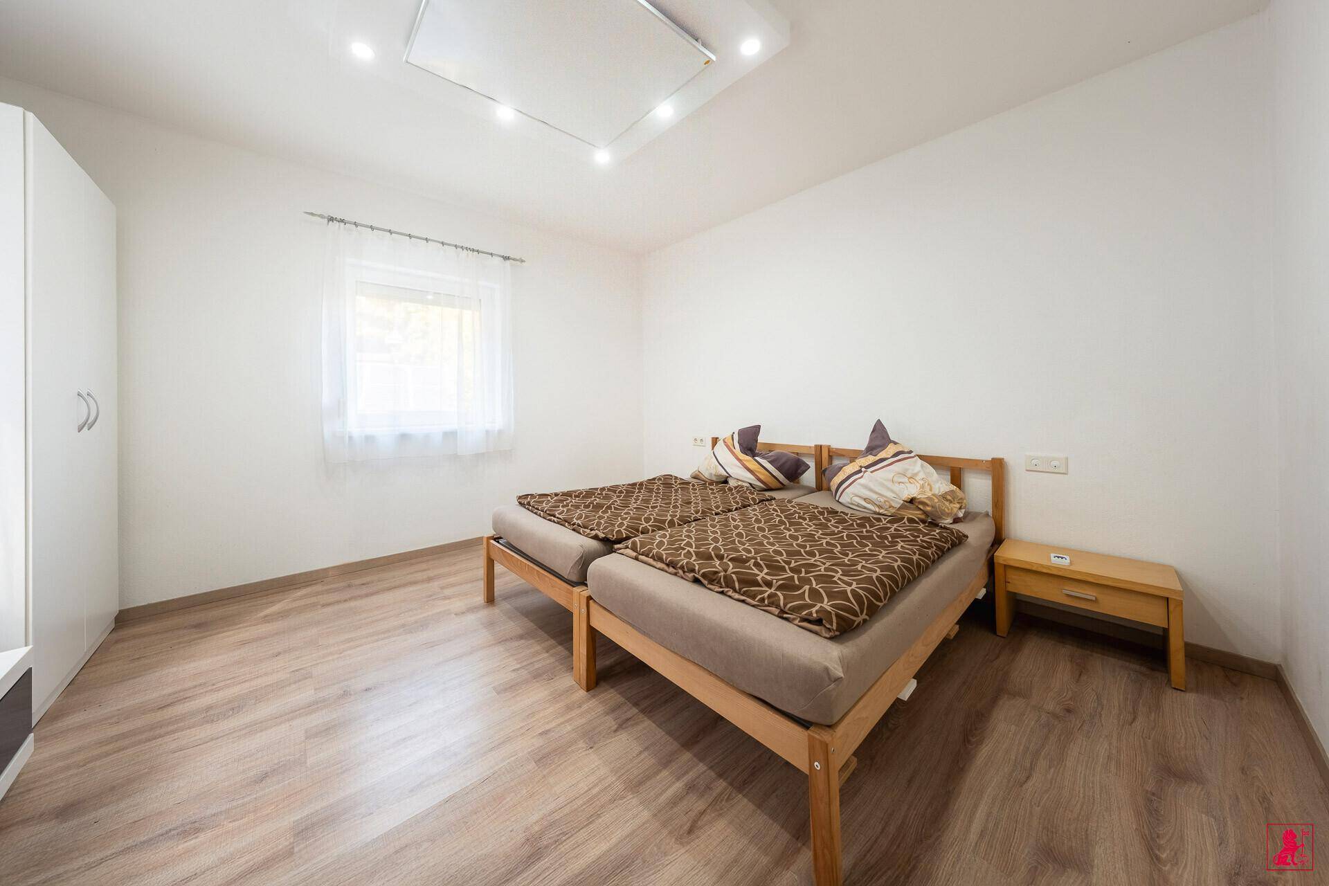 Schlafzimmer mit zwei Einzelbetten, Holzboden und weißem Kleiderschrank.