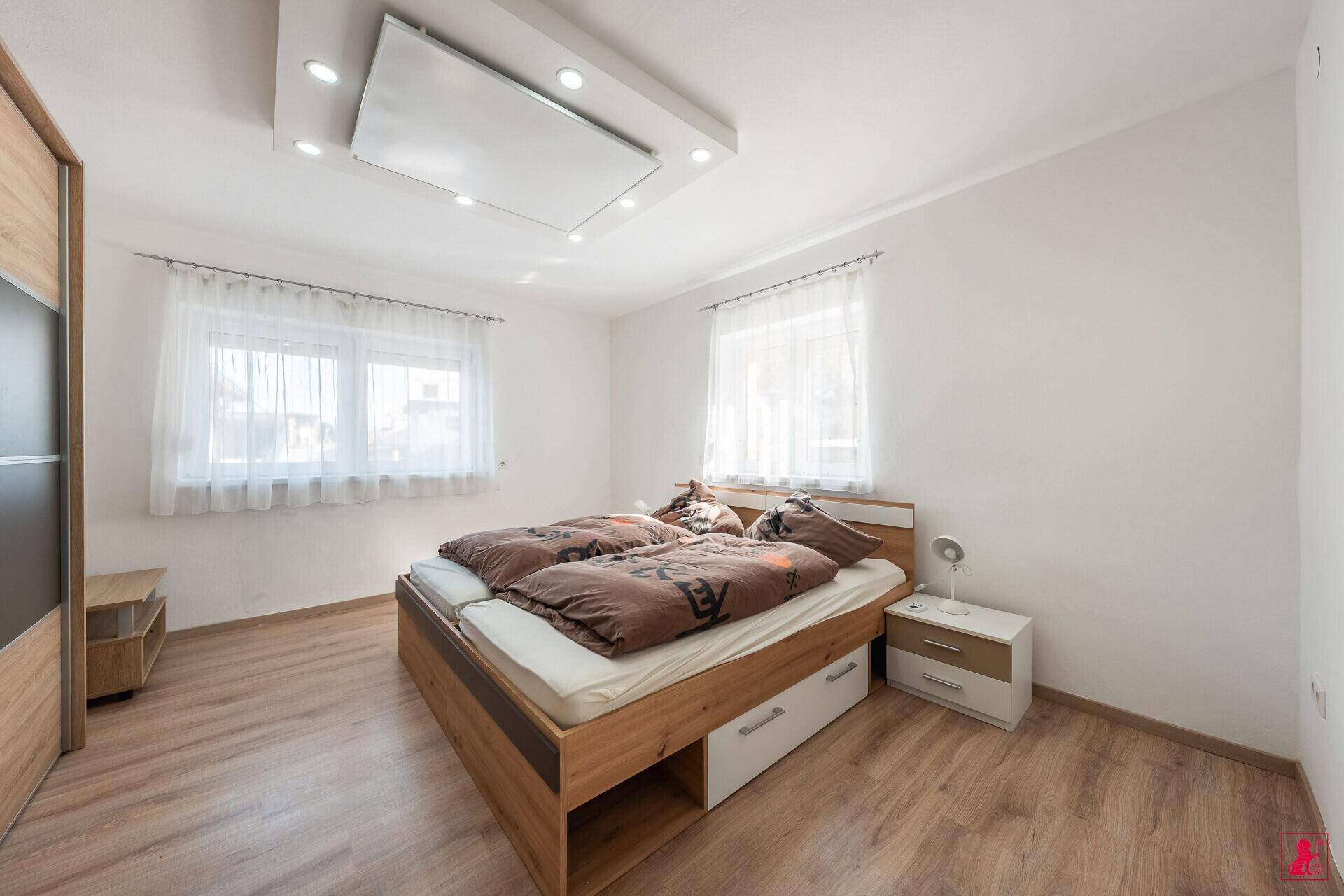 Helles Schlafzimmer mit Doppelbett, Holzboden und Einbauschrank.