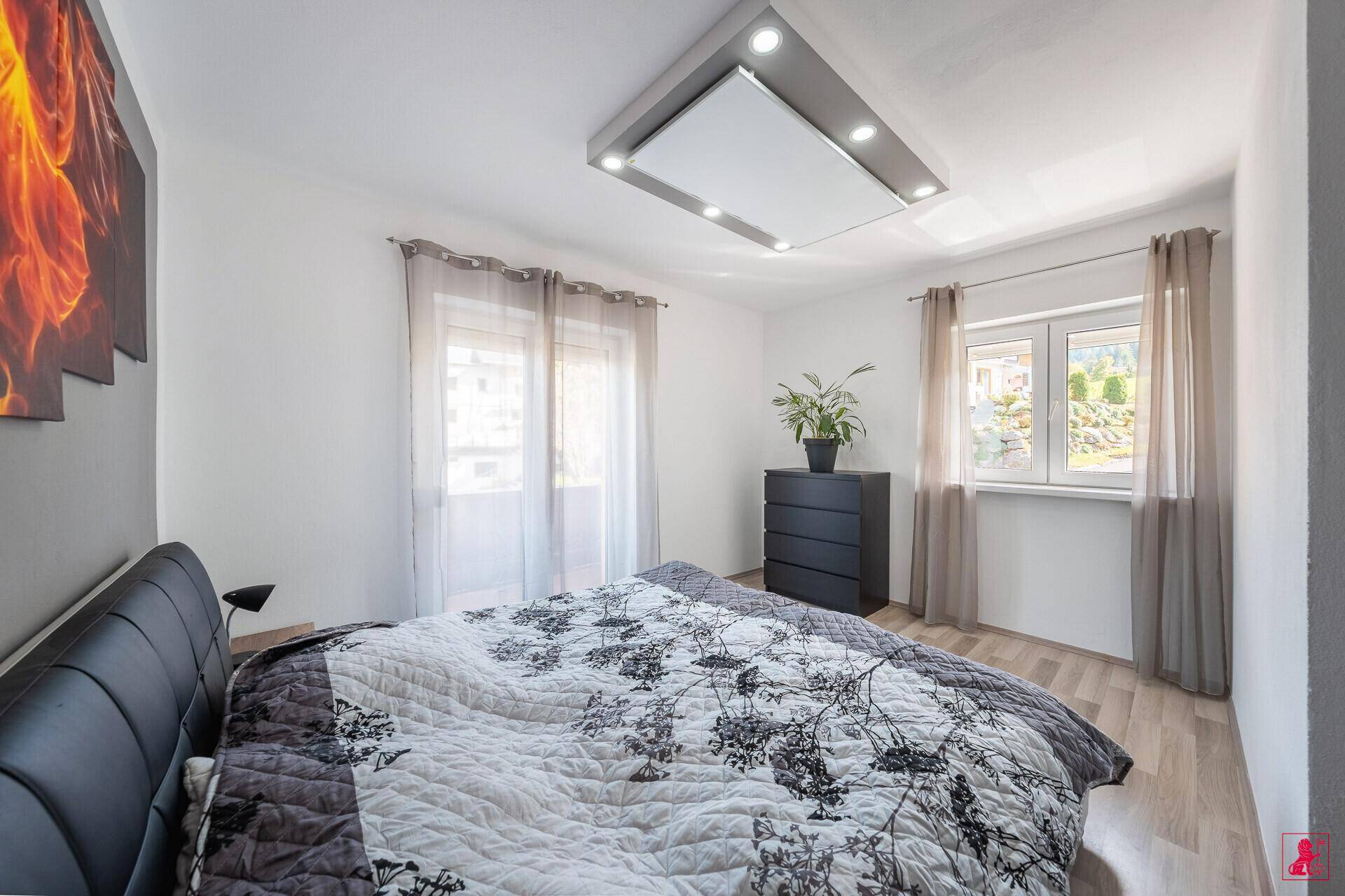 Gemütliches Schlafzimmer mit Doppelbett, Holzboden und Fenster.