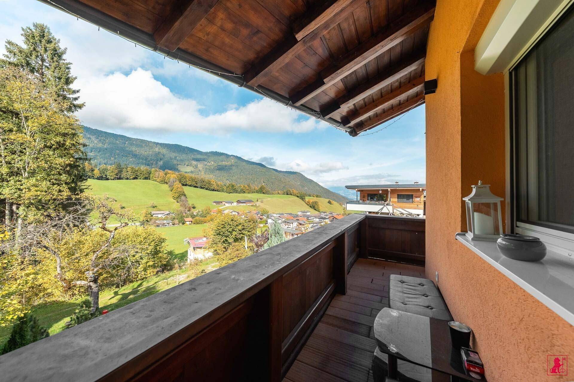 Geräumiger Holzbalkon mit Bergblick und Sitzgelegenheit.