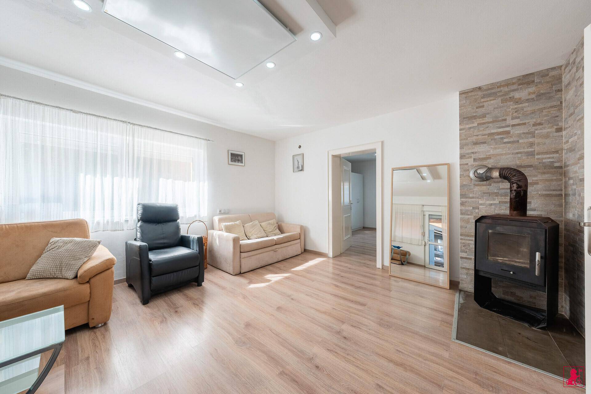 Helles Wohnzimmer mit Holzboden, Kaminofen und bequemen Sofas.