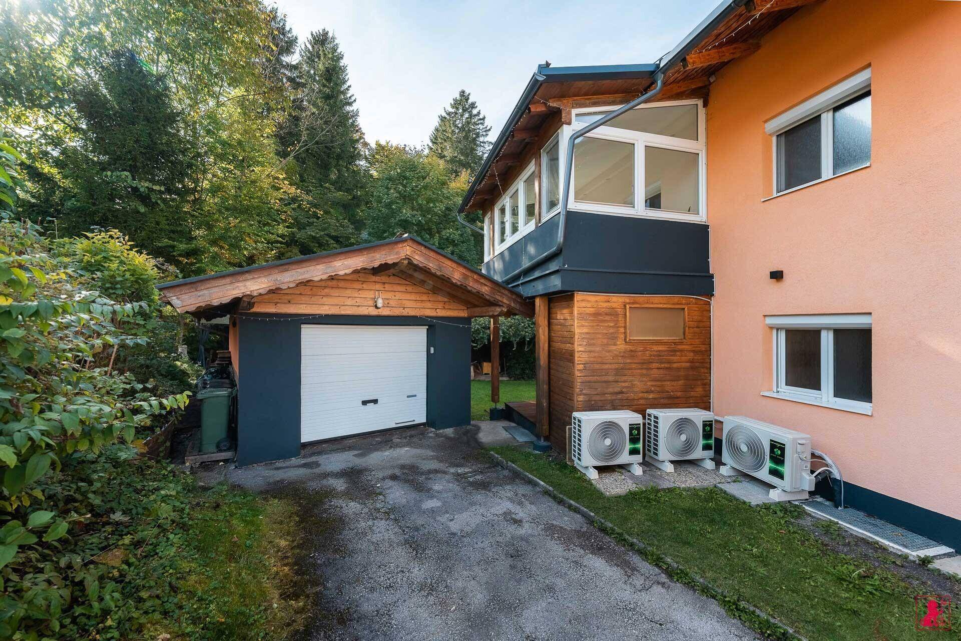 Seitenansicht des Hauses mit integrierter Garage und externen Klimaanlagen-Einheiten.