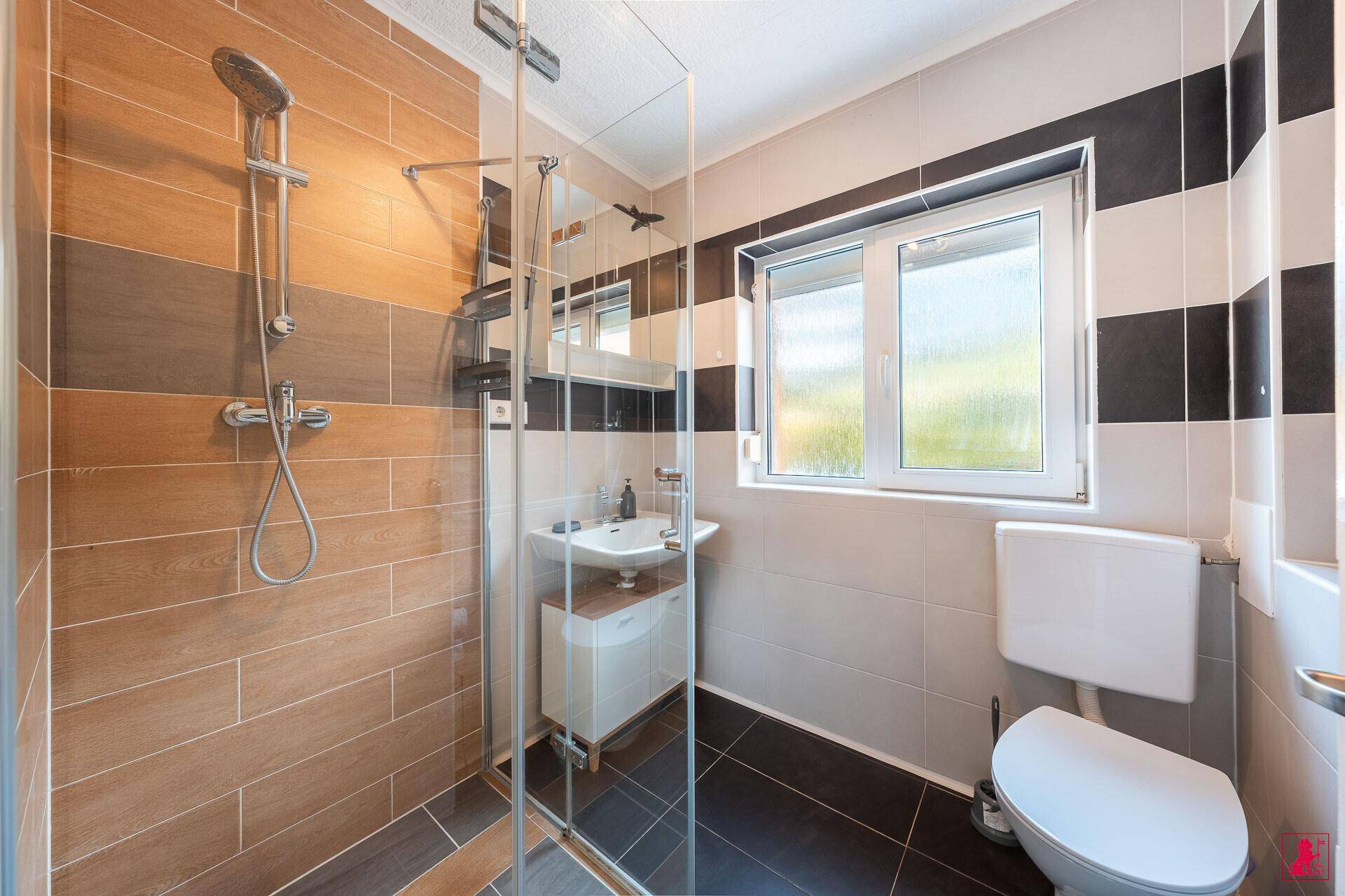 Modernes Badezimmer mit Dusche, Waschbecken und Fenster.