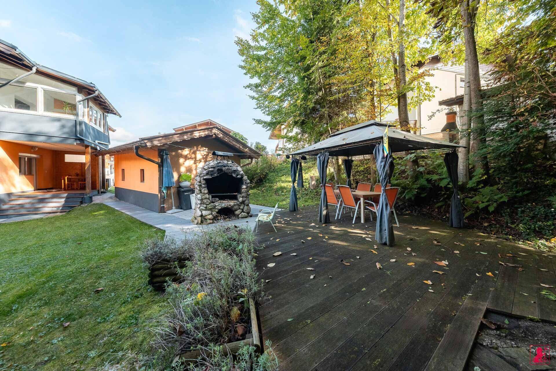 Großer Gartenbereich mit Grillplatz, Holzterrasse und Sitzgelegenheit.