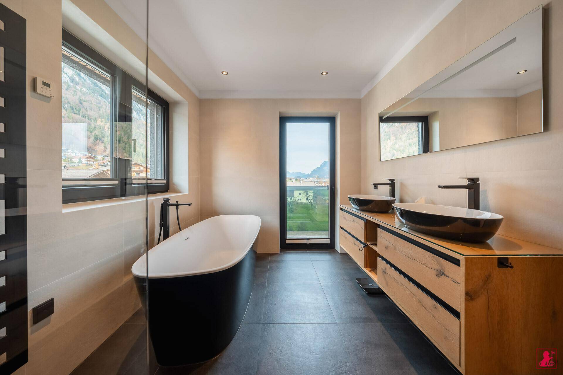 Modernes Badezimmer mit freistehender Badewanne, Doppelwaschbecken und Bergblick.