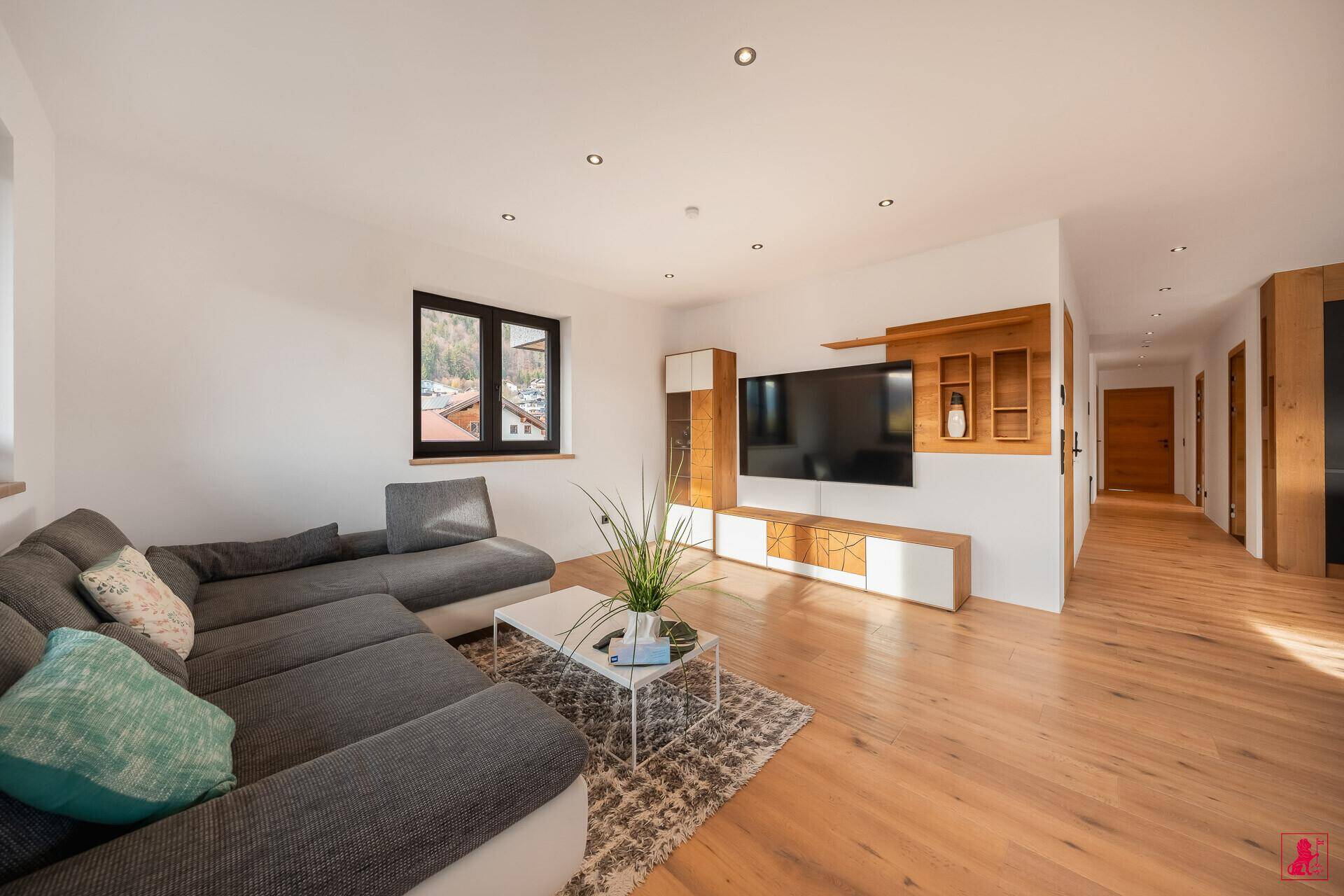 Gemütliches Wohnzimmer mit großem Ecksofa, Holzboden und modernem TV-Möbel.