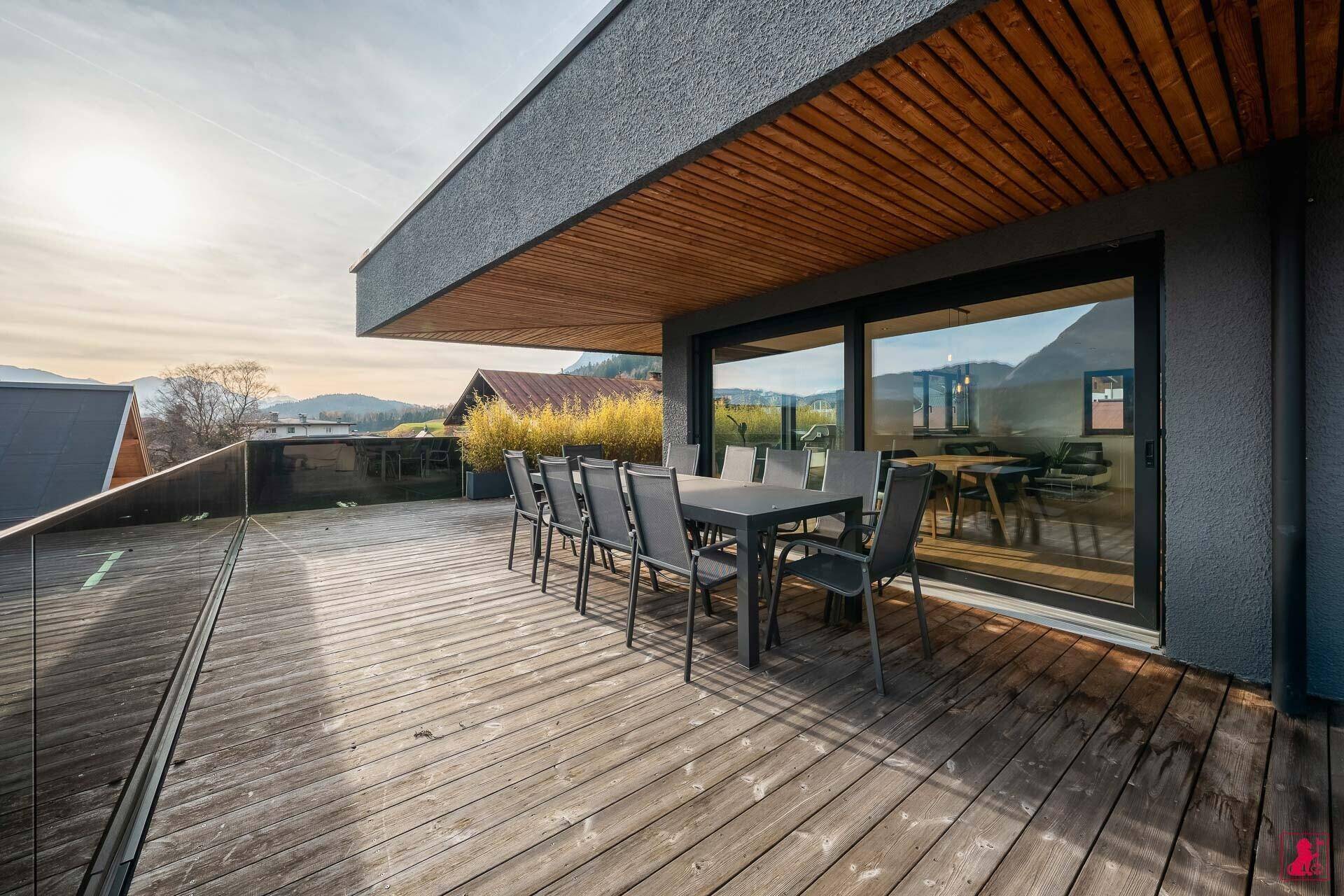 Geräumige Holzterrasse mit Esstisch und Stühlen, ideal für Mahlzeiten im Freien.