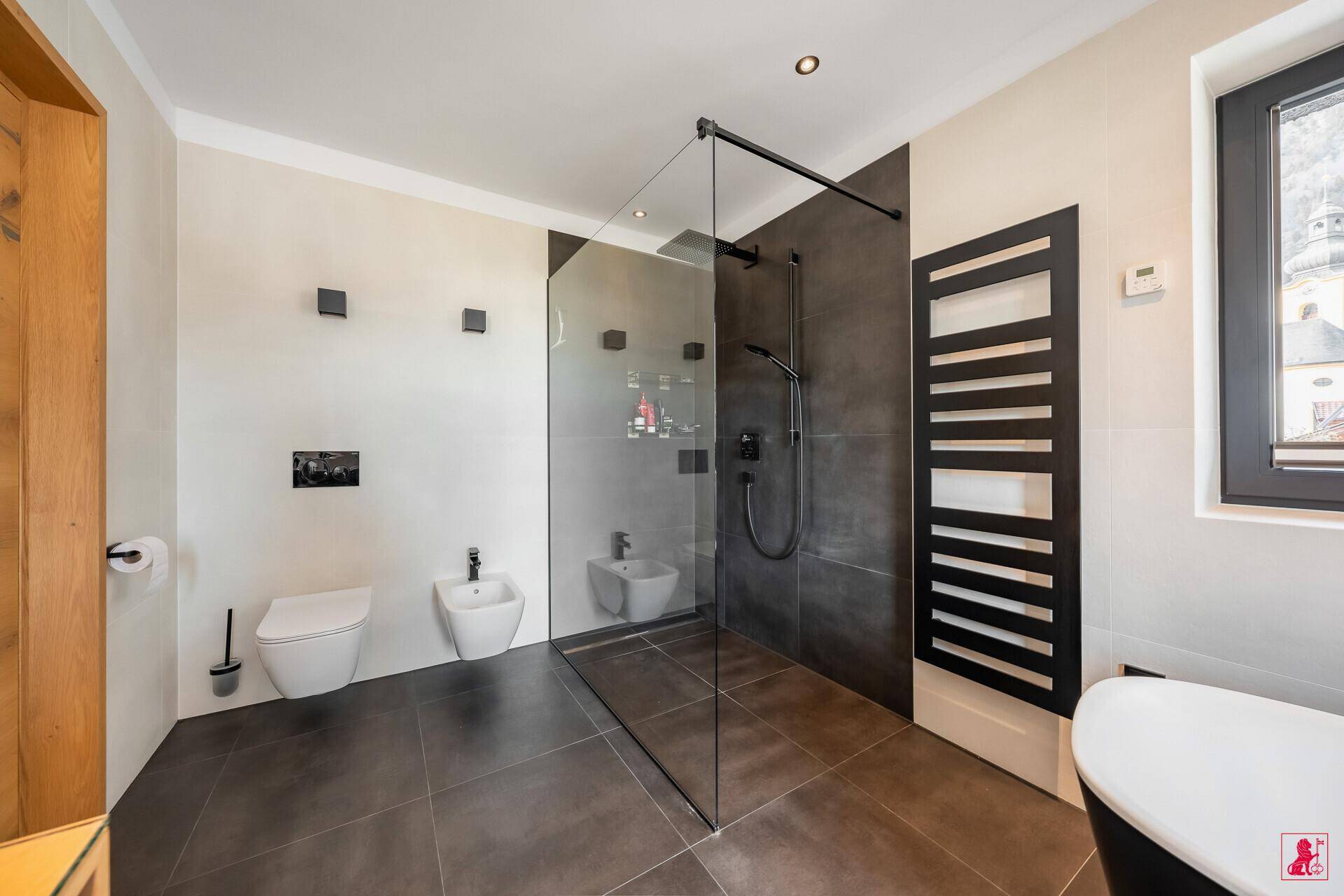 Elegantes Badezimmer mit ebenerdiger Dusche, Bidet und beheiztem Handtuchhalter.