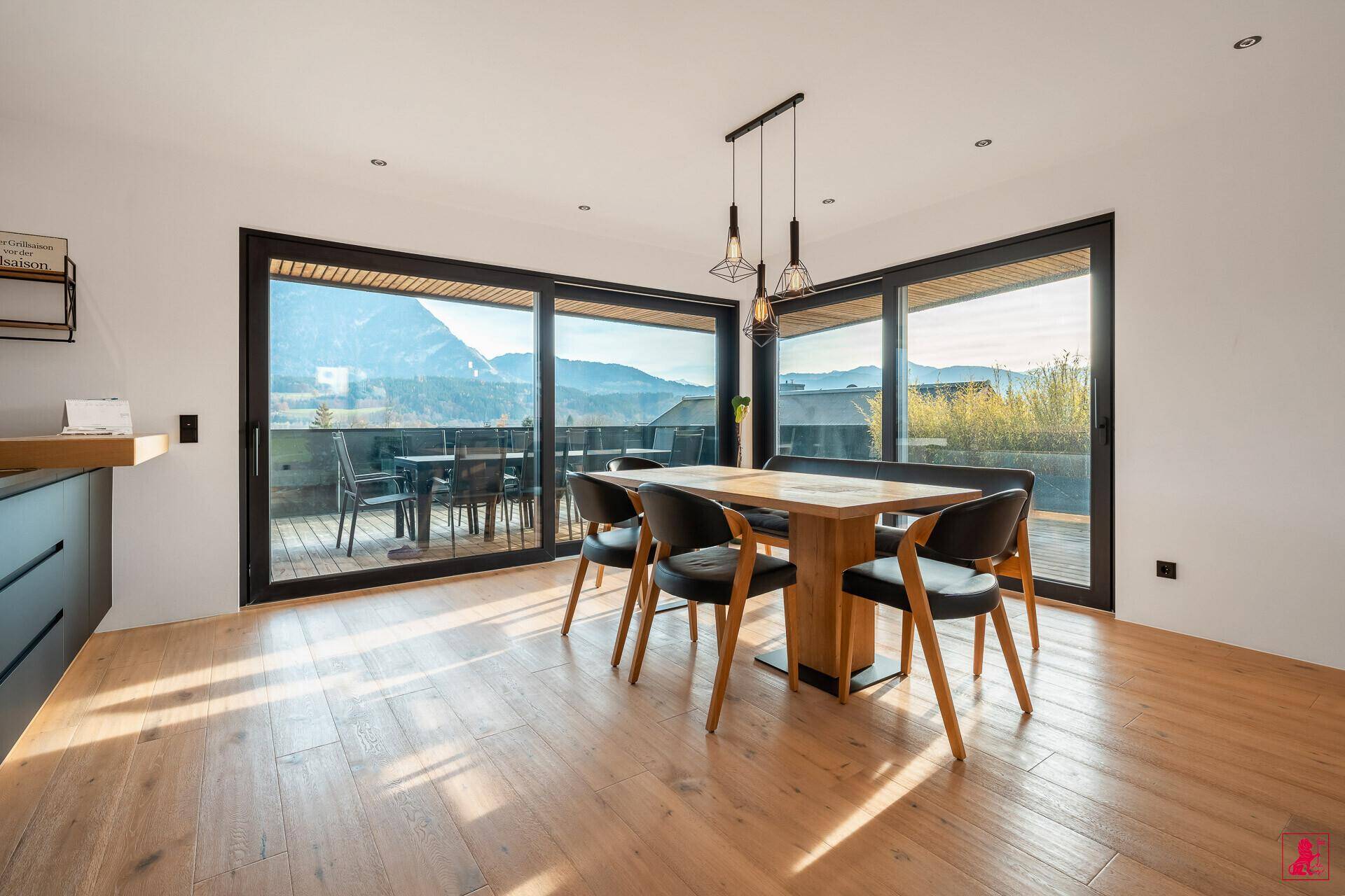 Heller Essbereich mit Holztisch, modernen Stühlen und weitem Blick auf die Berge.