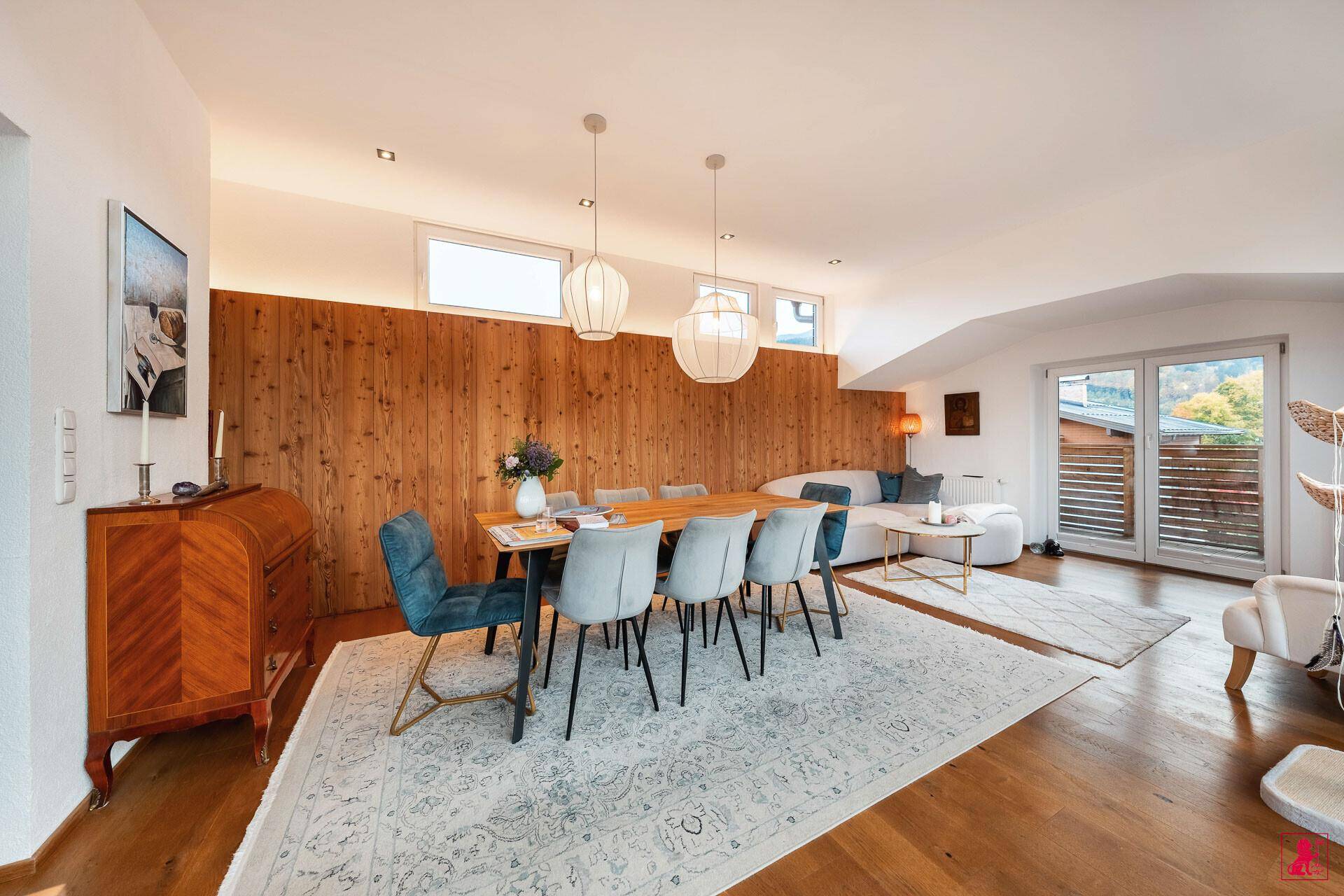 Geräumiger Wohn- und Essbereich mit Holzwand, modernen Möbeln und viel Licht.