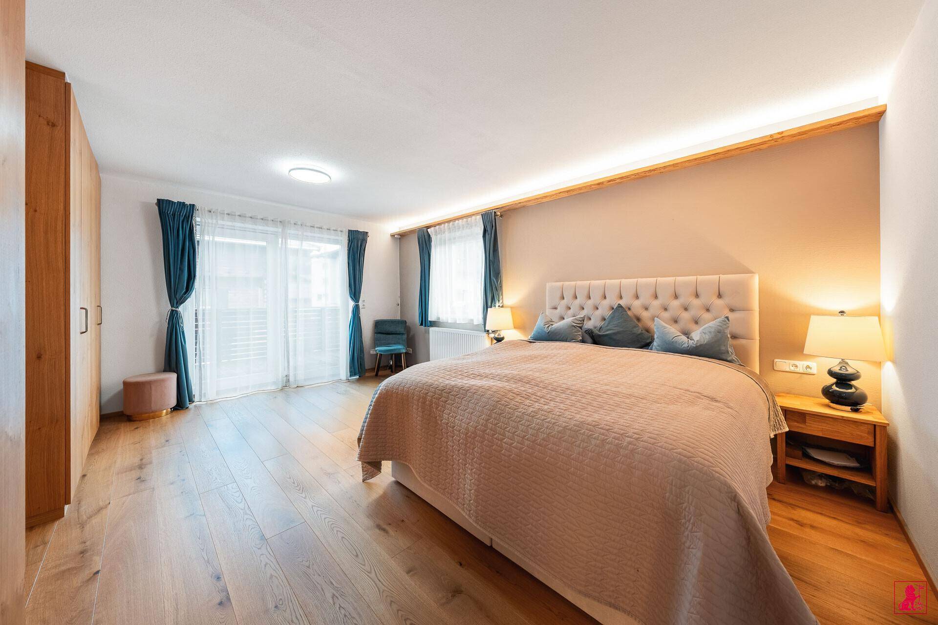 Gemütliches Schlafzimmer mit Holzboden, großem Bett und Zugang zum Balkon.