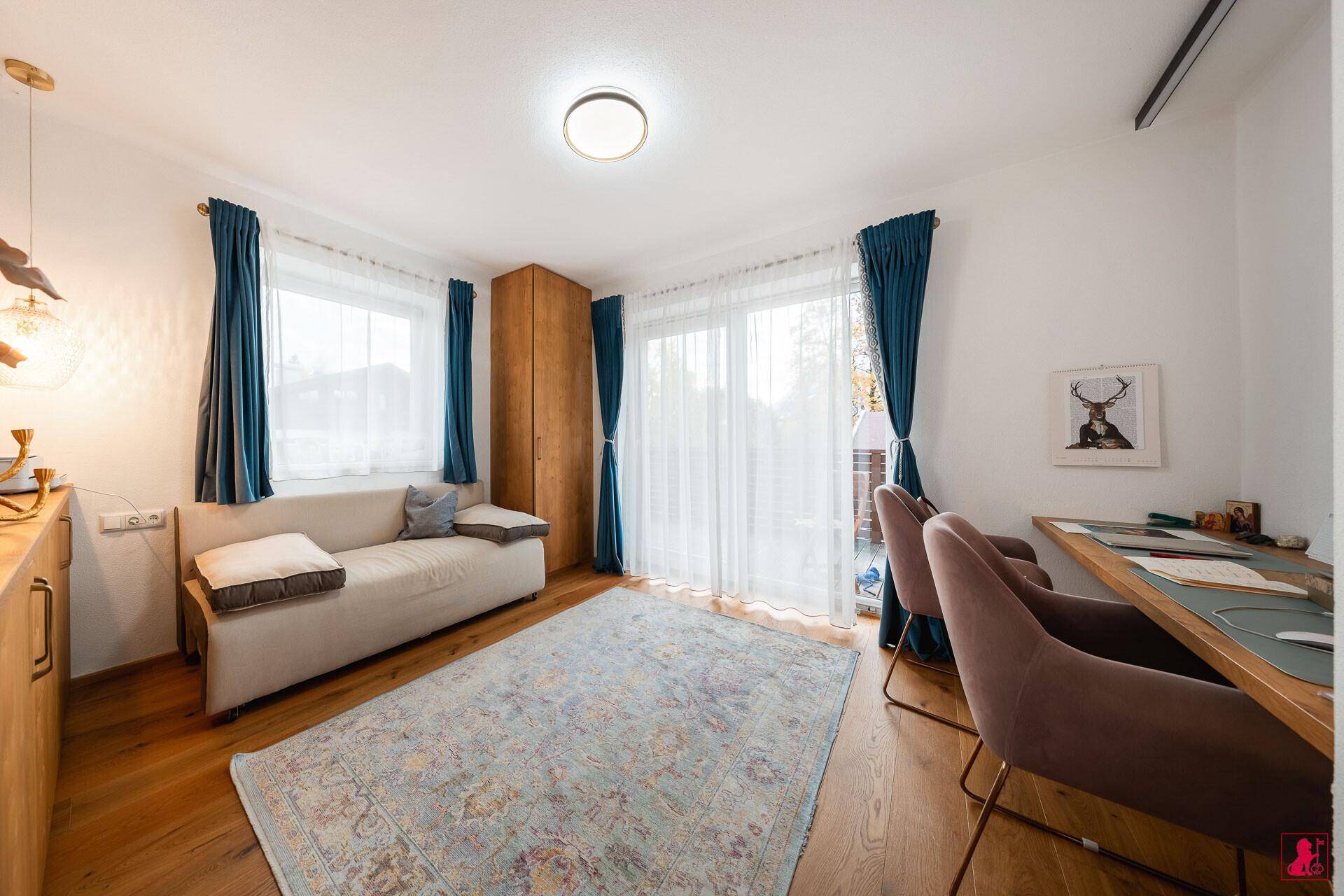 Helles Arbeitszimmer mit Holzboden, Schreibtisch und Zugang zu einem Balkon.