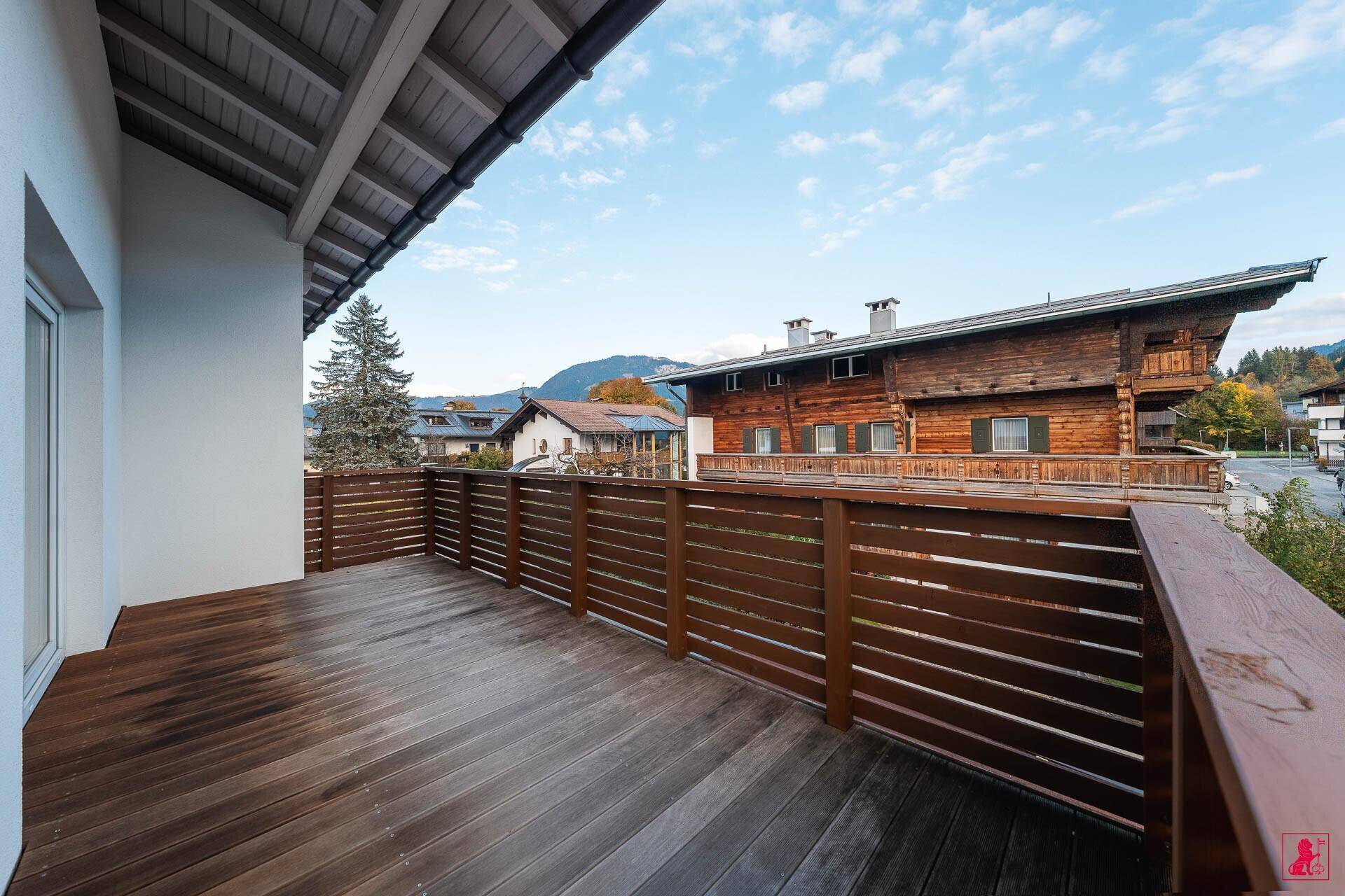 Geräumiger Holzbalkon mit Blick auf die umliegenden Häuser und Berge.