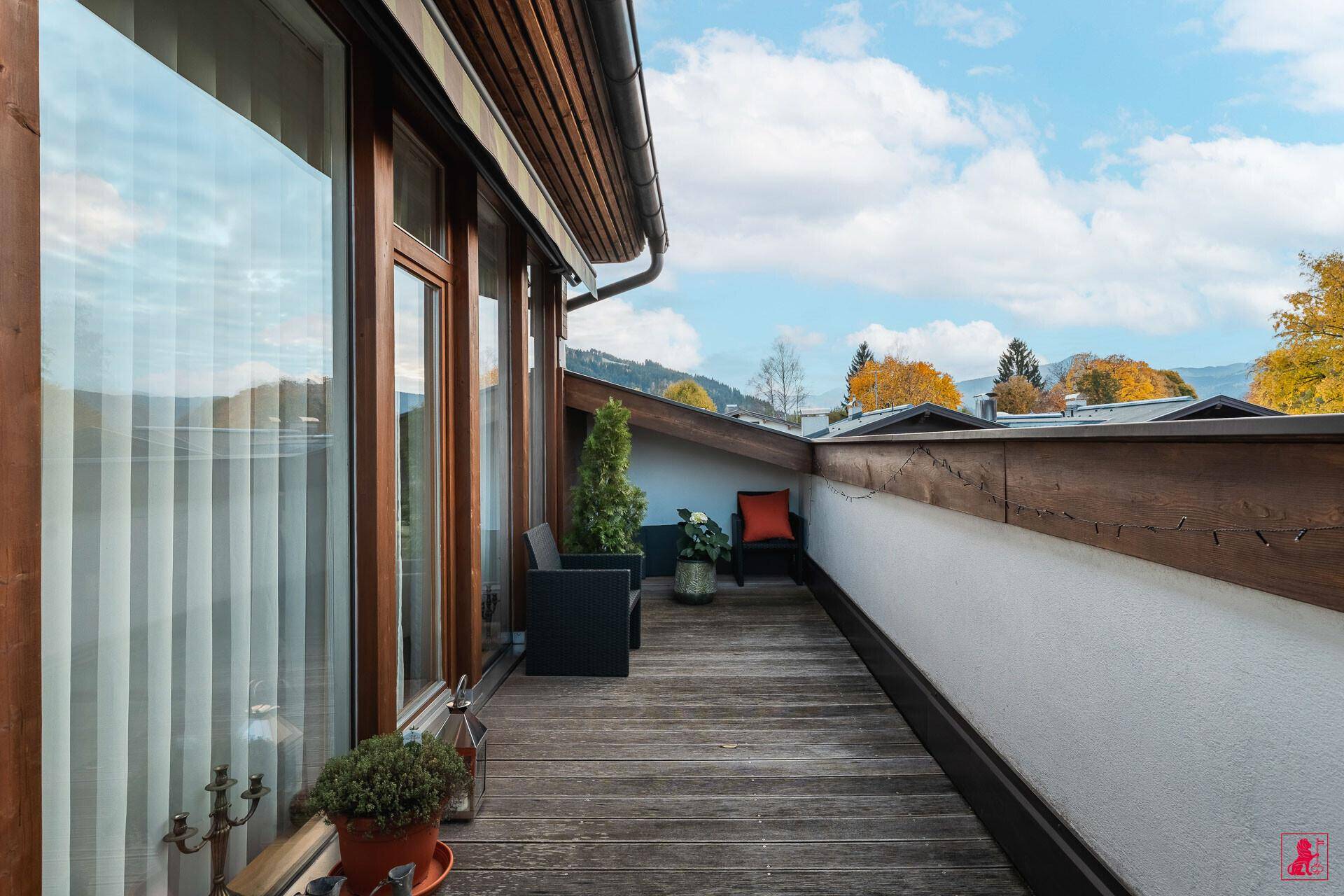 Langer Holzbalkon mit Sitzgelegenheiten und weitem Blick auf die Landschaft.