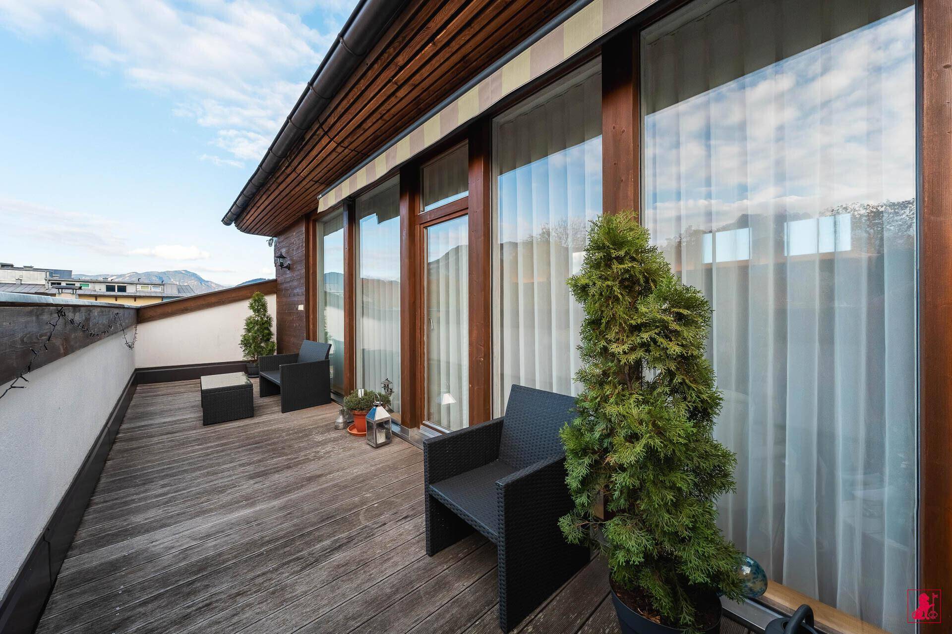 Breiter Holzbalkon mit Pflanzen und Blick auf die umliegende Natur.