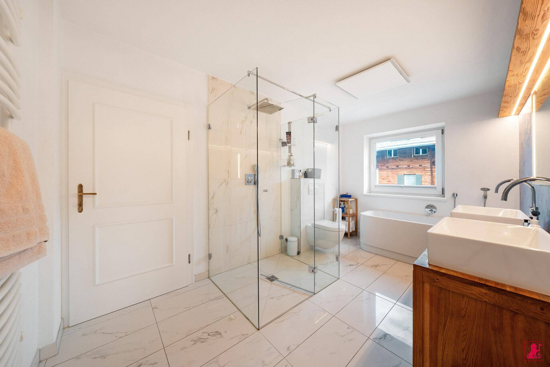 Helles Badezimmer mit Badewanne, begehbarer Dusche und beheiztem Handtuchhalter.